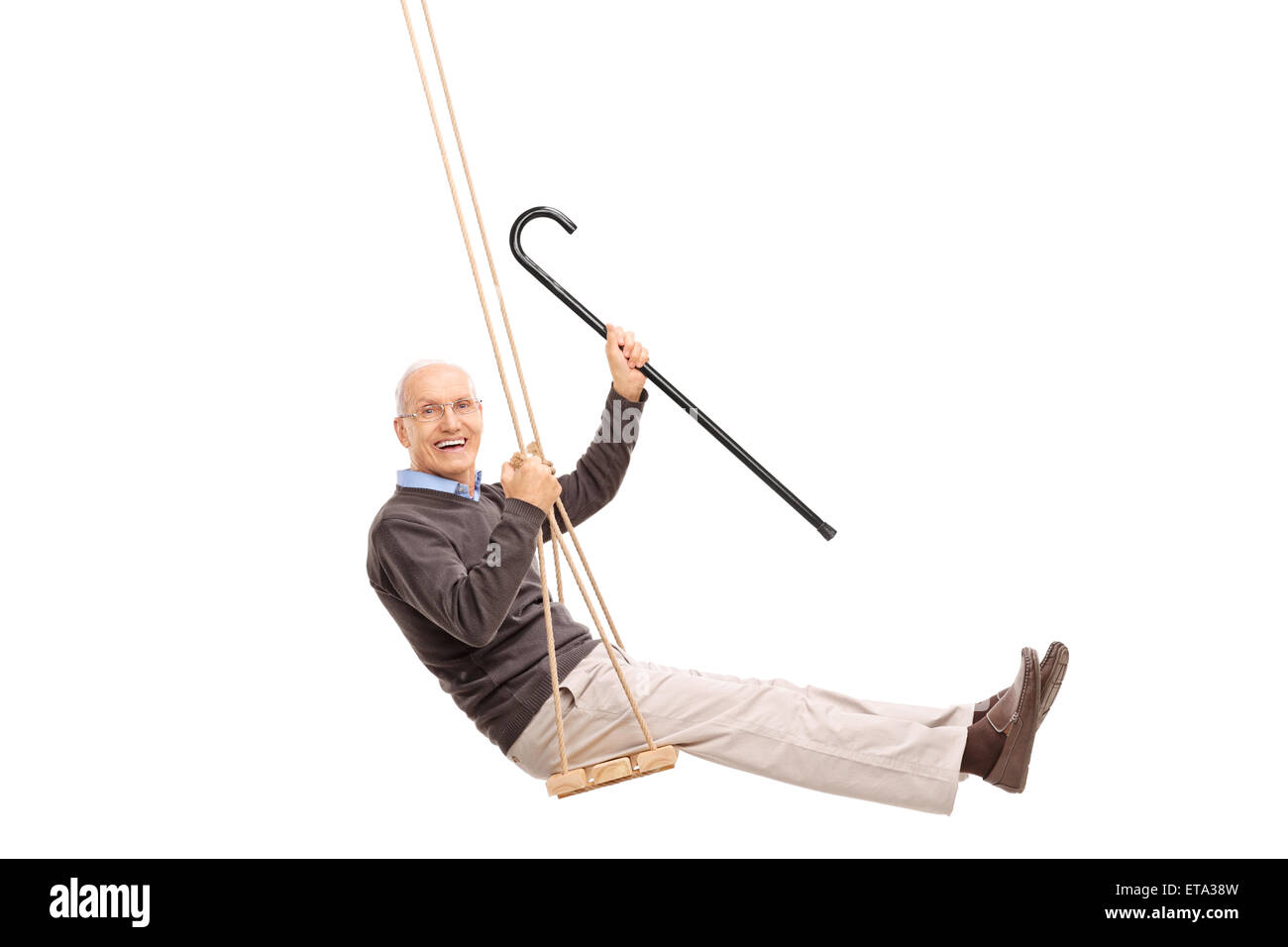 Studio shot of a joyful senior swinging on a swing and holding a cane isolated on white background Stock Photo