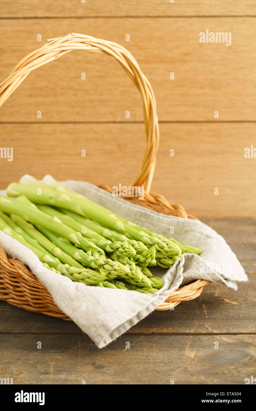 Green asparagus bunch on wicker tray on white table background