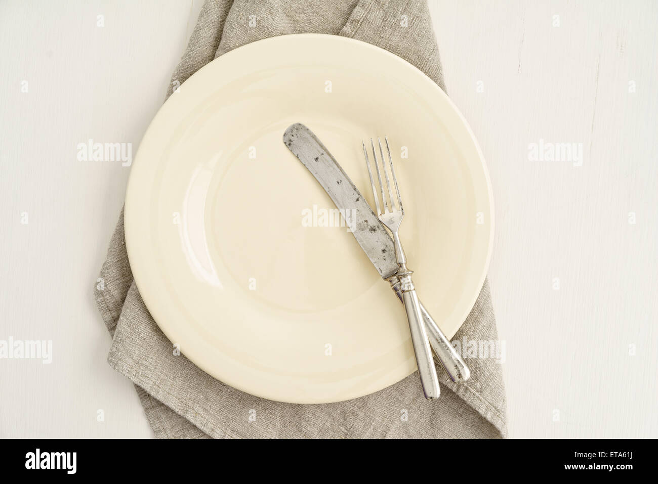 Empty beige plate with vintage silverware on linen cloth Stock Photo
