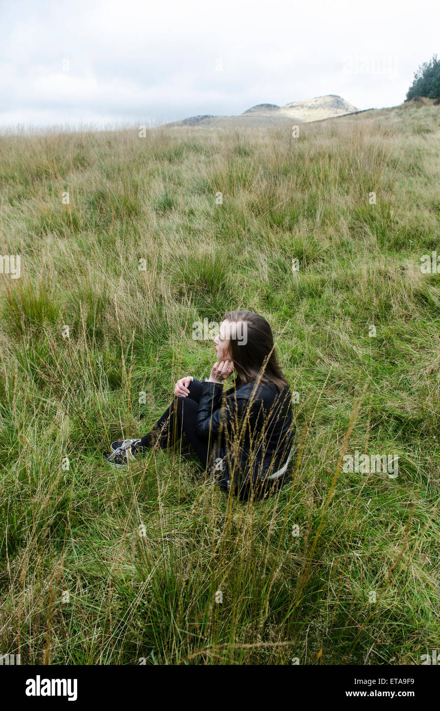 Lonely woman sat in the field Stock Photo