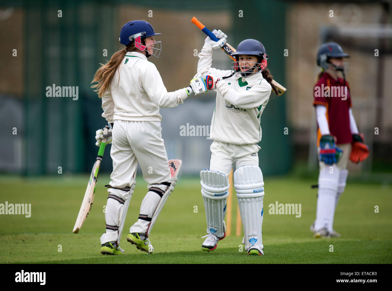A batsman celebrates her 50 junior during a girls cricket match in Wiltshire UK Stock Photo