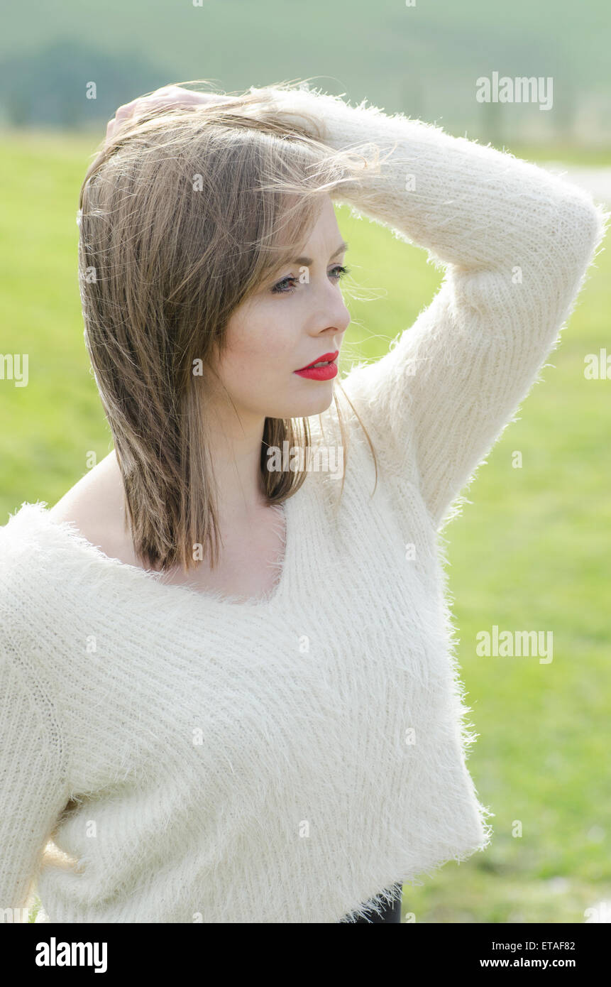 Beautiful young woman hand touching hair looking away Stock Photo - Alamy