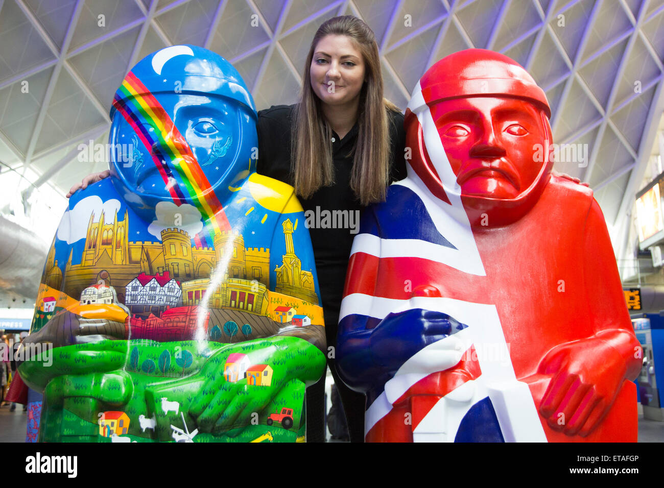 London, UK. Alison Grice, 22, of Visit Lincoln poses with the Lincoln Barons. Two Lincoln's Magna Carta Barons were today displayed at London's King's Cross Station before going back up to Lincoln tomorrow. Almost exactly 800 years since King John put his seal to Magna Carta, Lincoln is set to welcome a reincarnation of his 25 Barons into the city’s streets. The Lincoln Barons’ Charter Trail will see 25 2m-tall sculptures decorated by renowned artists from Lincolnshire and beyond.  Local businesses and organisations have worked with the artists to devise a different theme for each Baron. The t Stock Photo