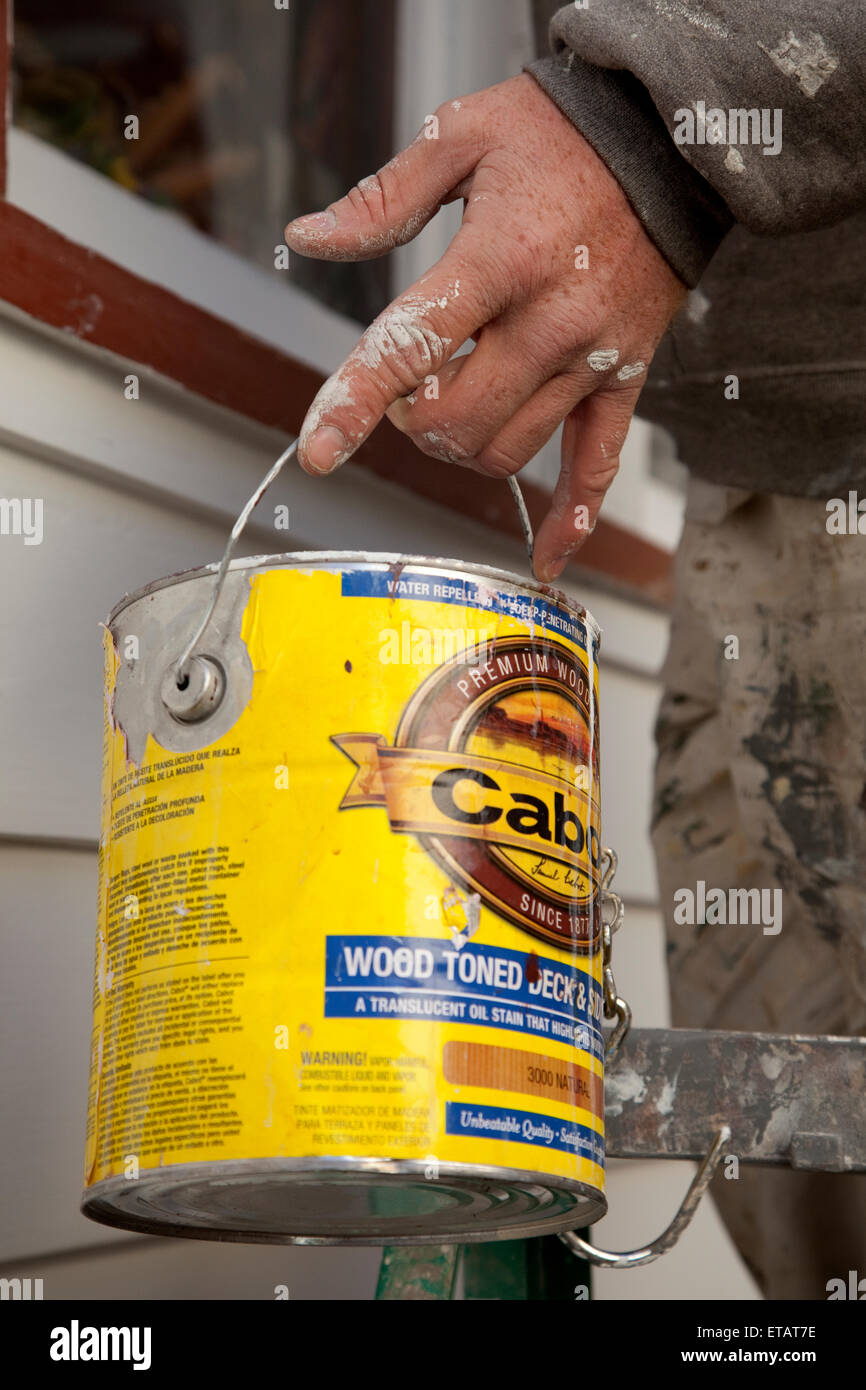 Painters hand holding bucket of paint as he paints house. St Paul