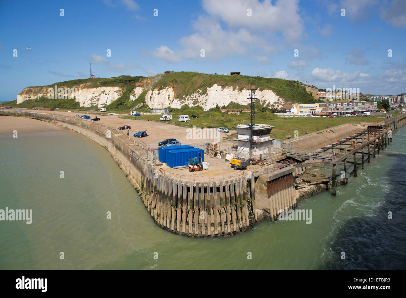 Port of Newhaven harbour entrance. The old disused harbour control building dominates the quayside with car park beyond. Stock Photo