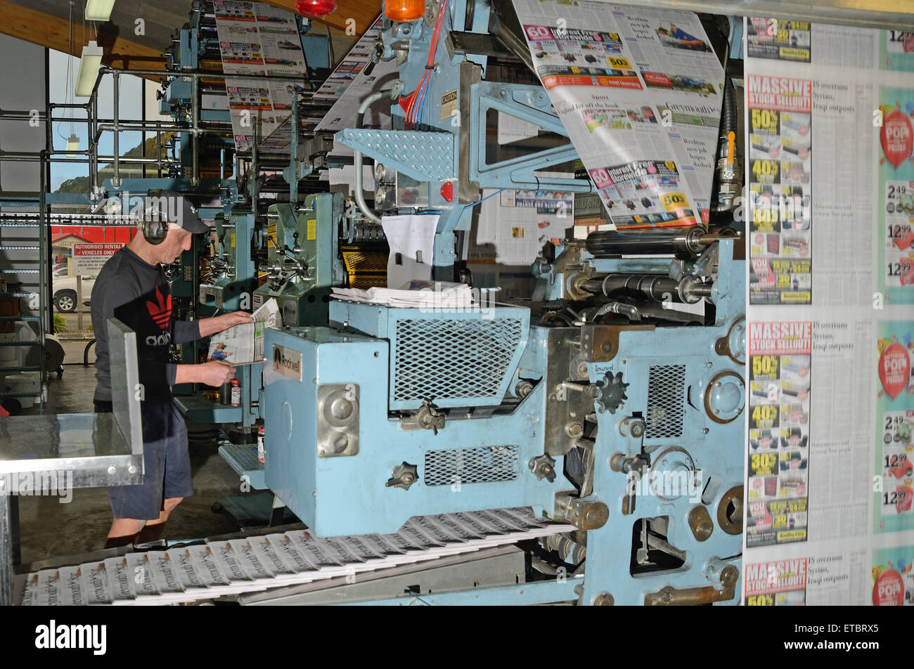 GREYMOUTH, NEW ZEALAND, MAY 22, 2015:  An unidentified printer checks the quality of his workmanship while printing a newspaper Stock Photo