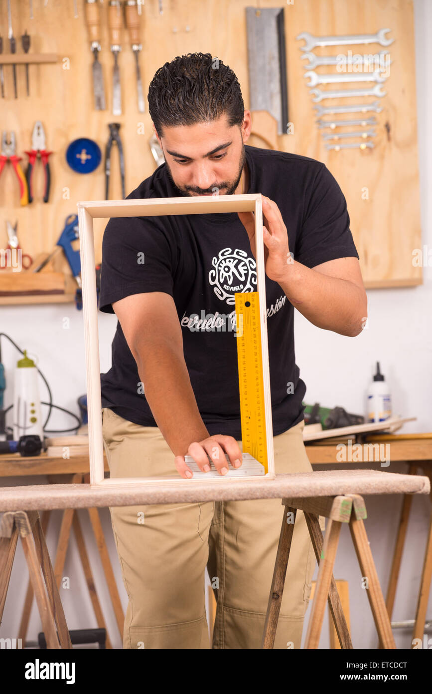 Skilled artisan measuring the frame of an unfinished percussion instrument Stock Photo