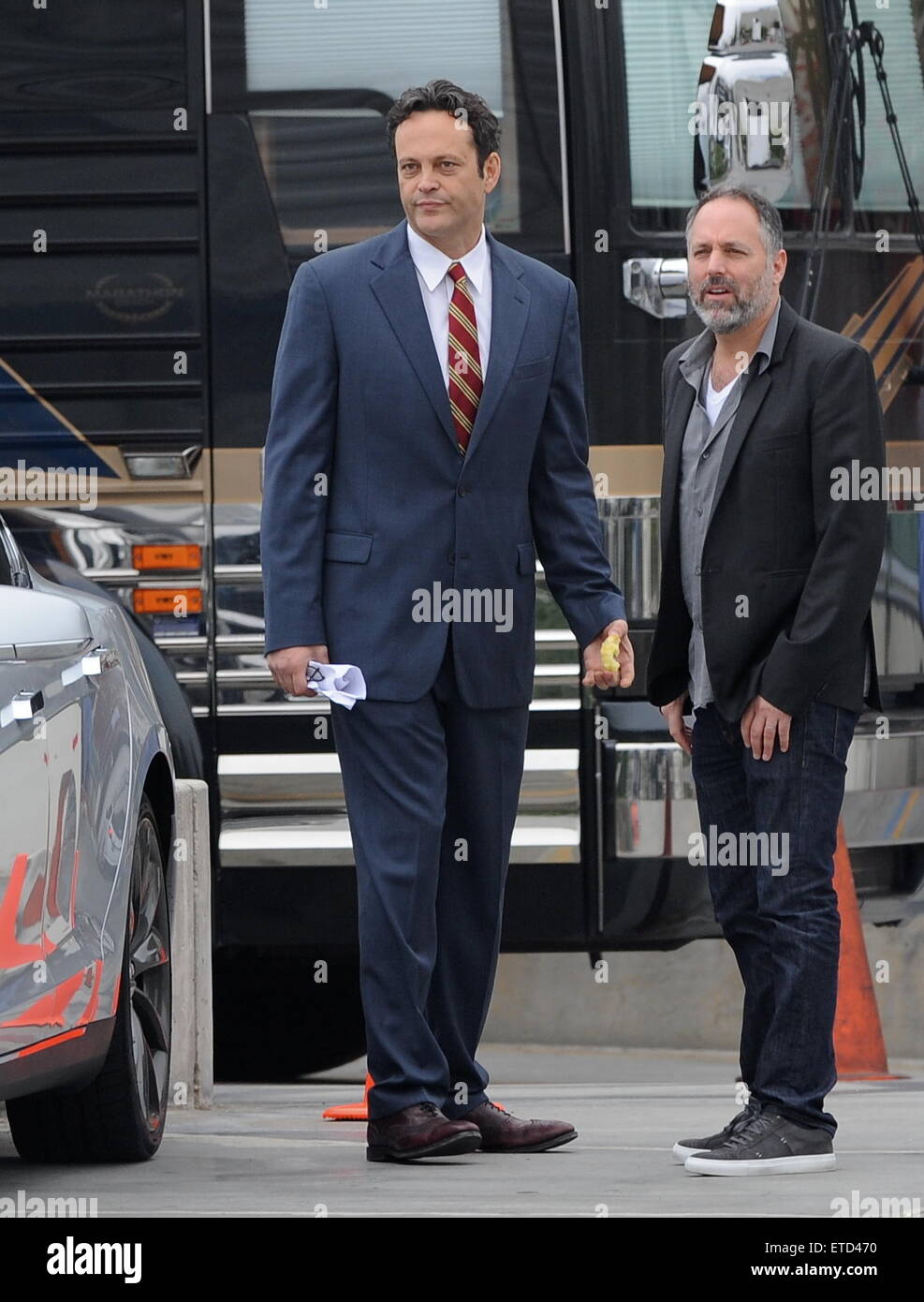 Actor Vince Vaughn wearing a blue suit while eating an apple on the set of  \, image size:987x1390