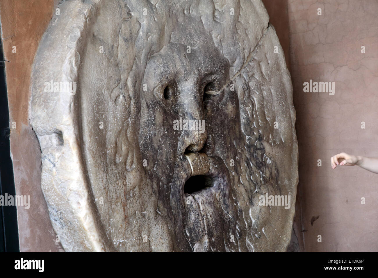 A hand about to enter the Bocca della Verita or Mouth of Truth in St Mary in Cosmedin in Rome. Stock Photo