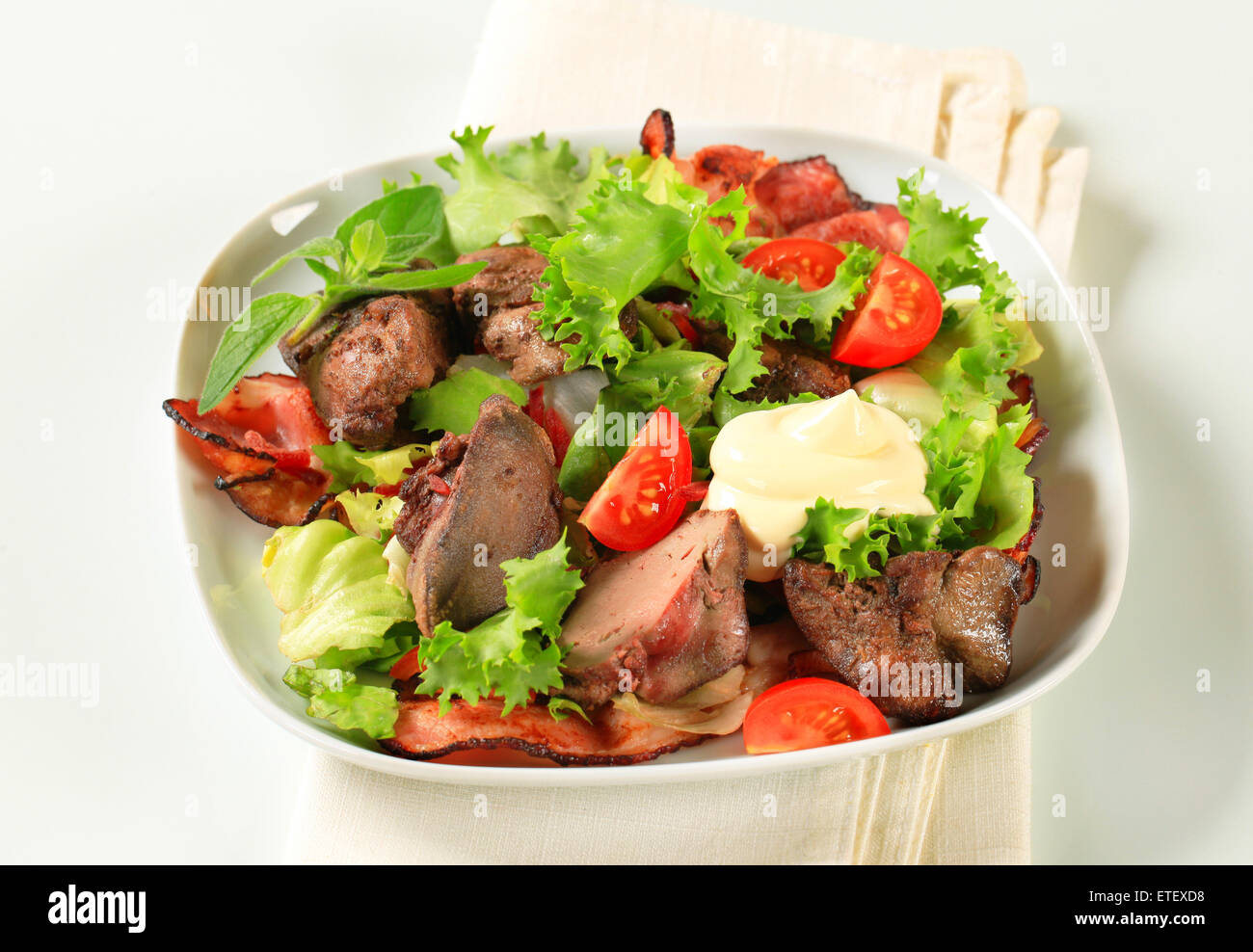 Pan fried chicken livers with salad greens and bacon strips Stock Photo