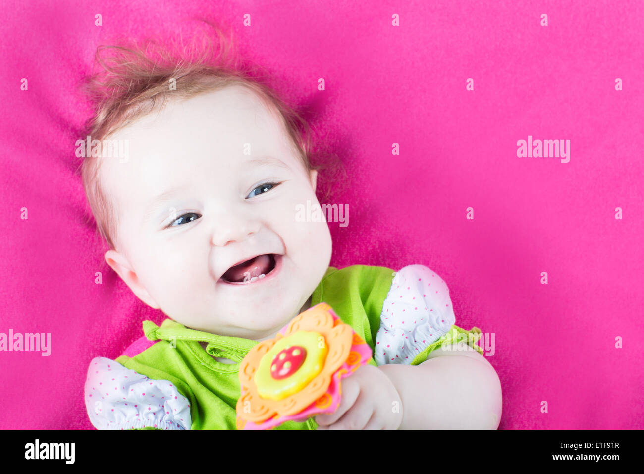 Baby girl playing with her toy flower on a pink blanket Stock Photo - Alamy