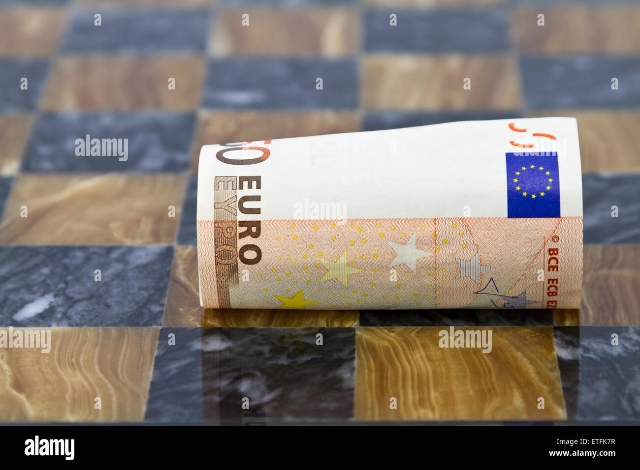 Close focus on euro currency unrolling on chess board.  Symbols of challenges in euro market, banking, and business. Stock Photo