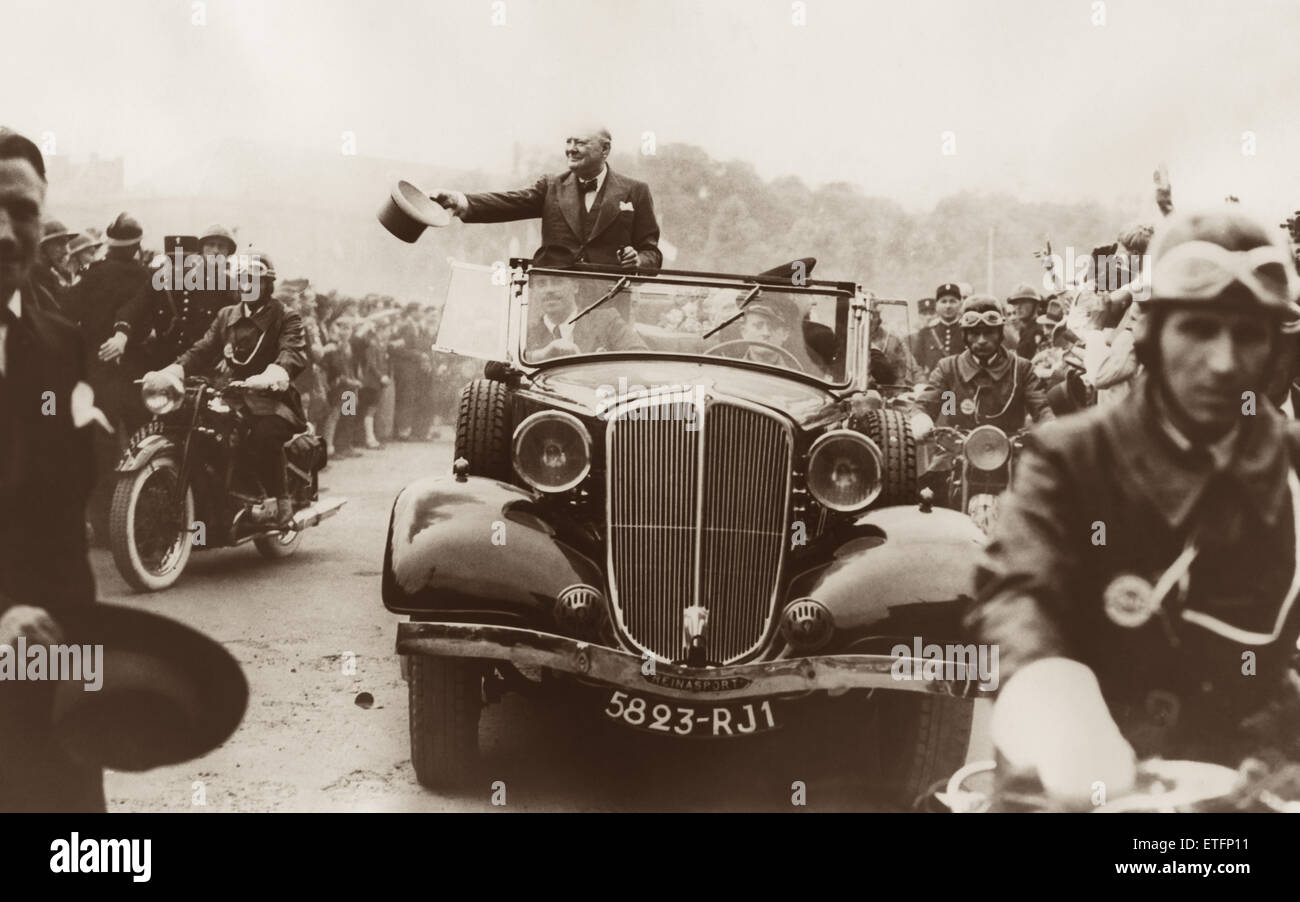 Winston Churchill waving his new gray top hat while being driven through the welcoming crowds in Metz, France where the British Prime Minister was guest of honor at the Fortress City's Bastille Day (July 14th) celebration. Stock Photo