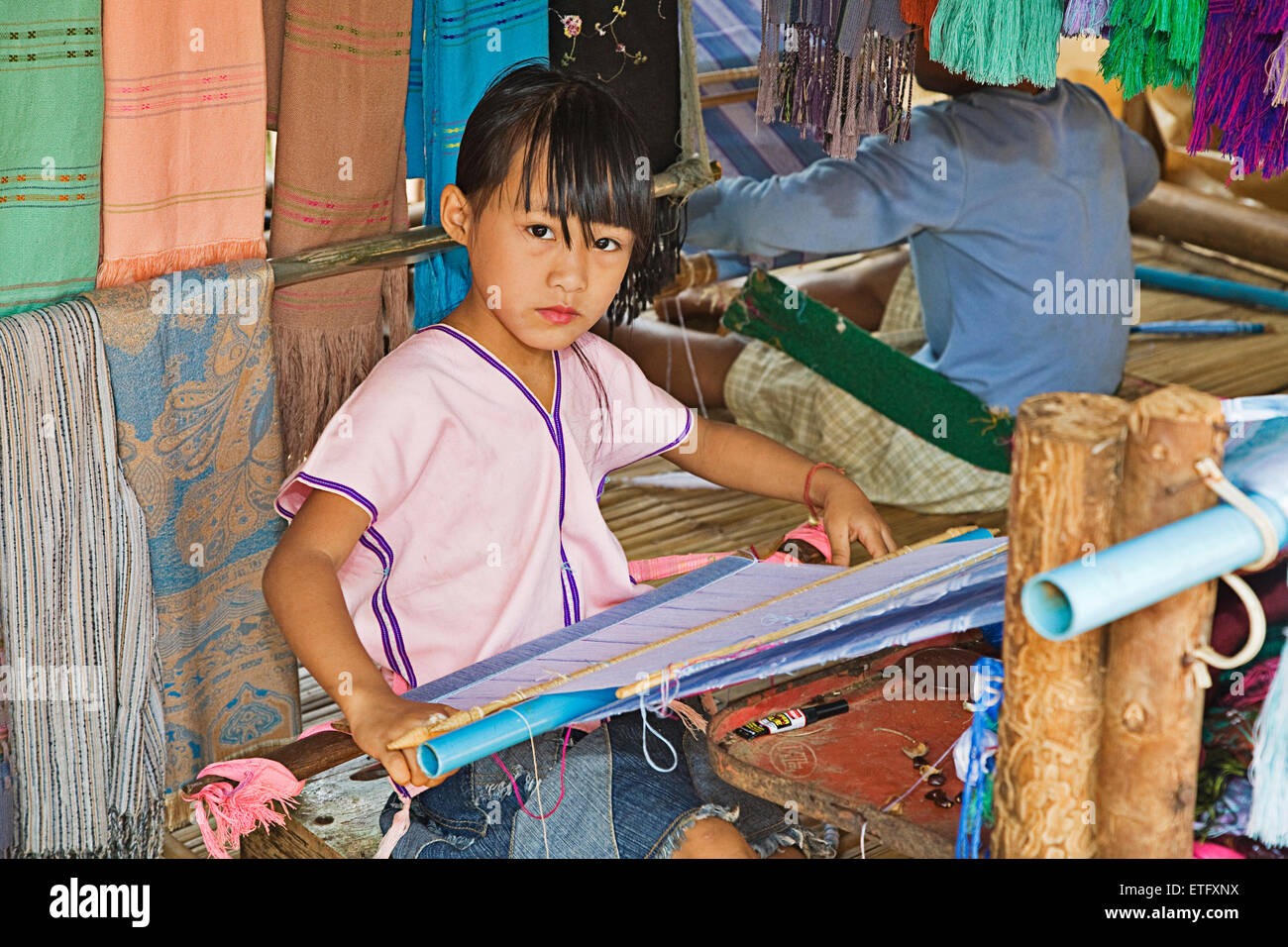 A young girl working at  the loom in the hill tribes village near Chiang Mai. Stock Photo
