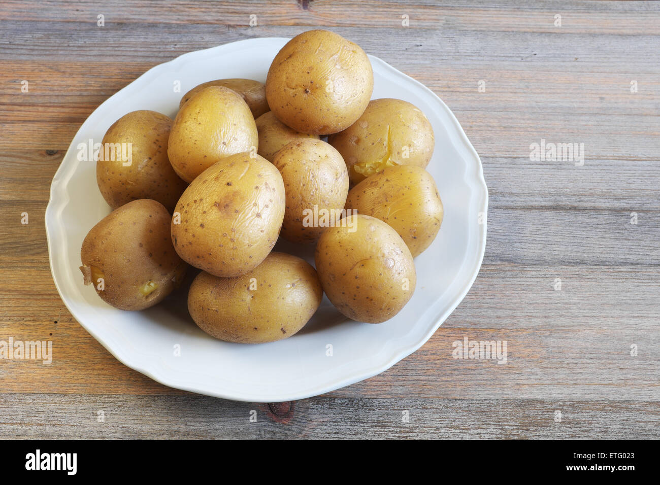 boiled potatoes in their skins on a plate, wooden background Stock Photo