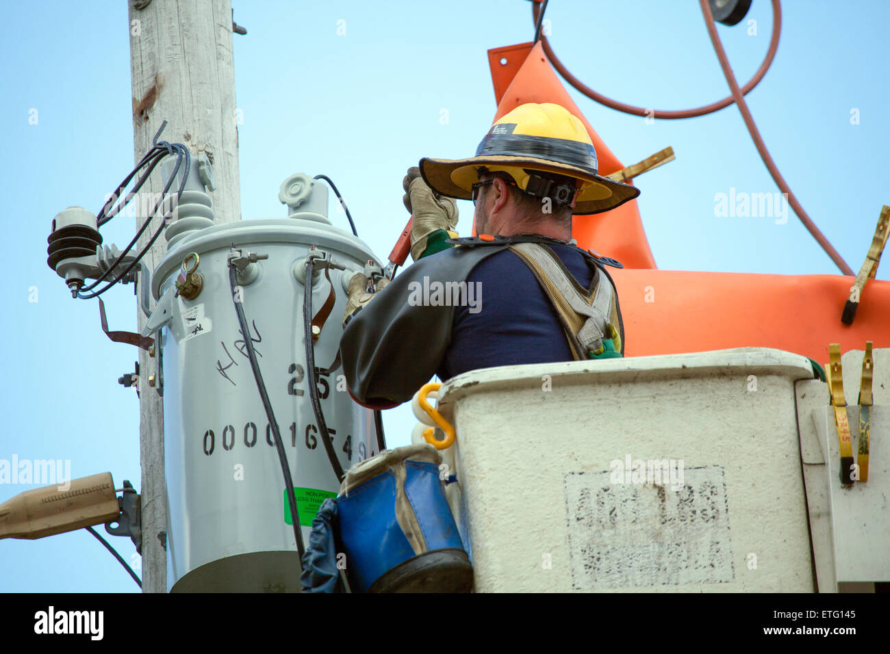 An electrical line worker repairs overhead power lines using a cherry