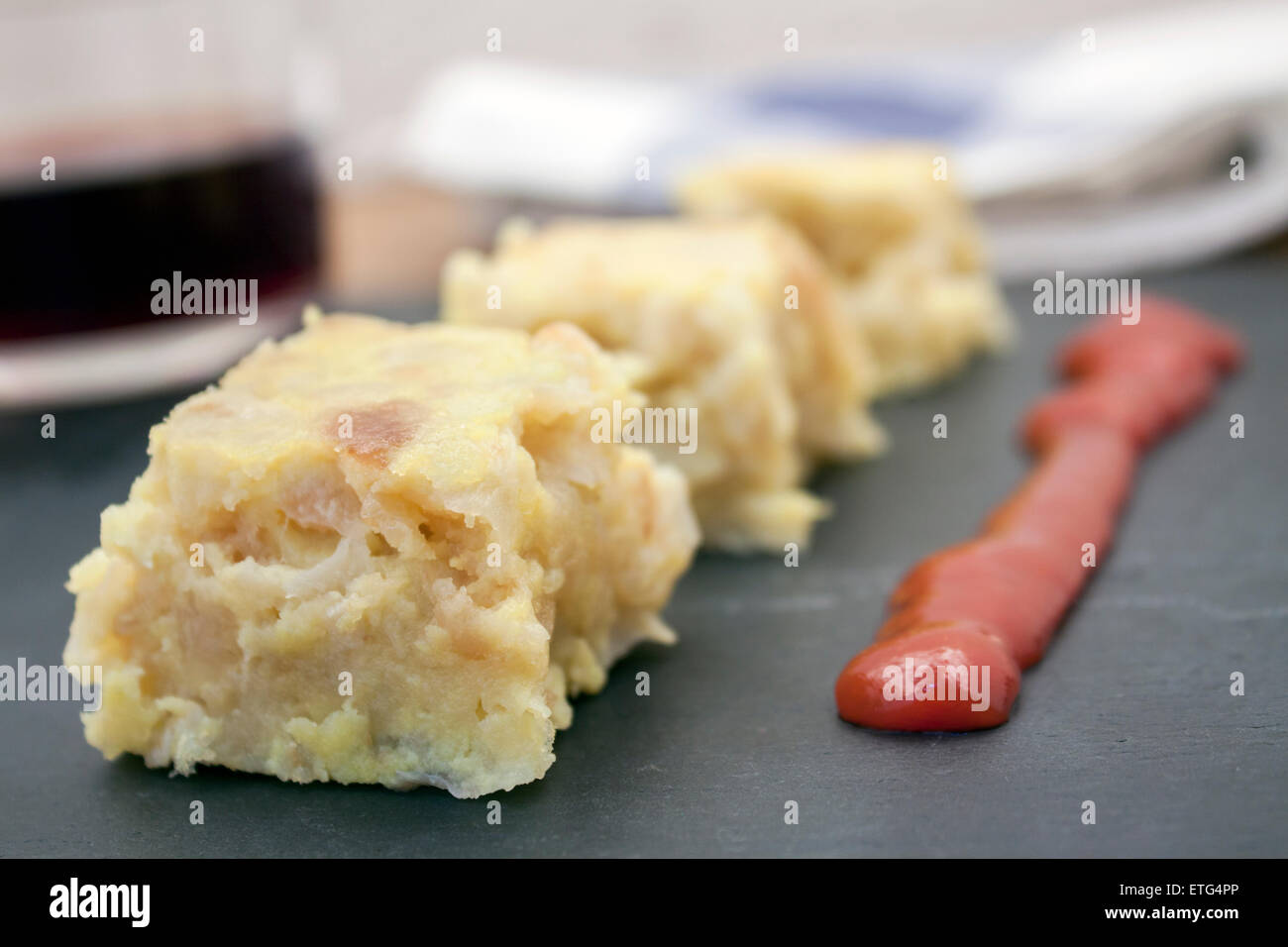 a delicious tapa of spanish tradicional omelet with sauce and a glass