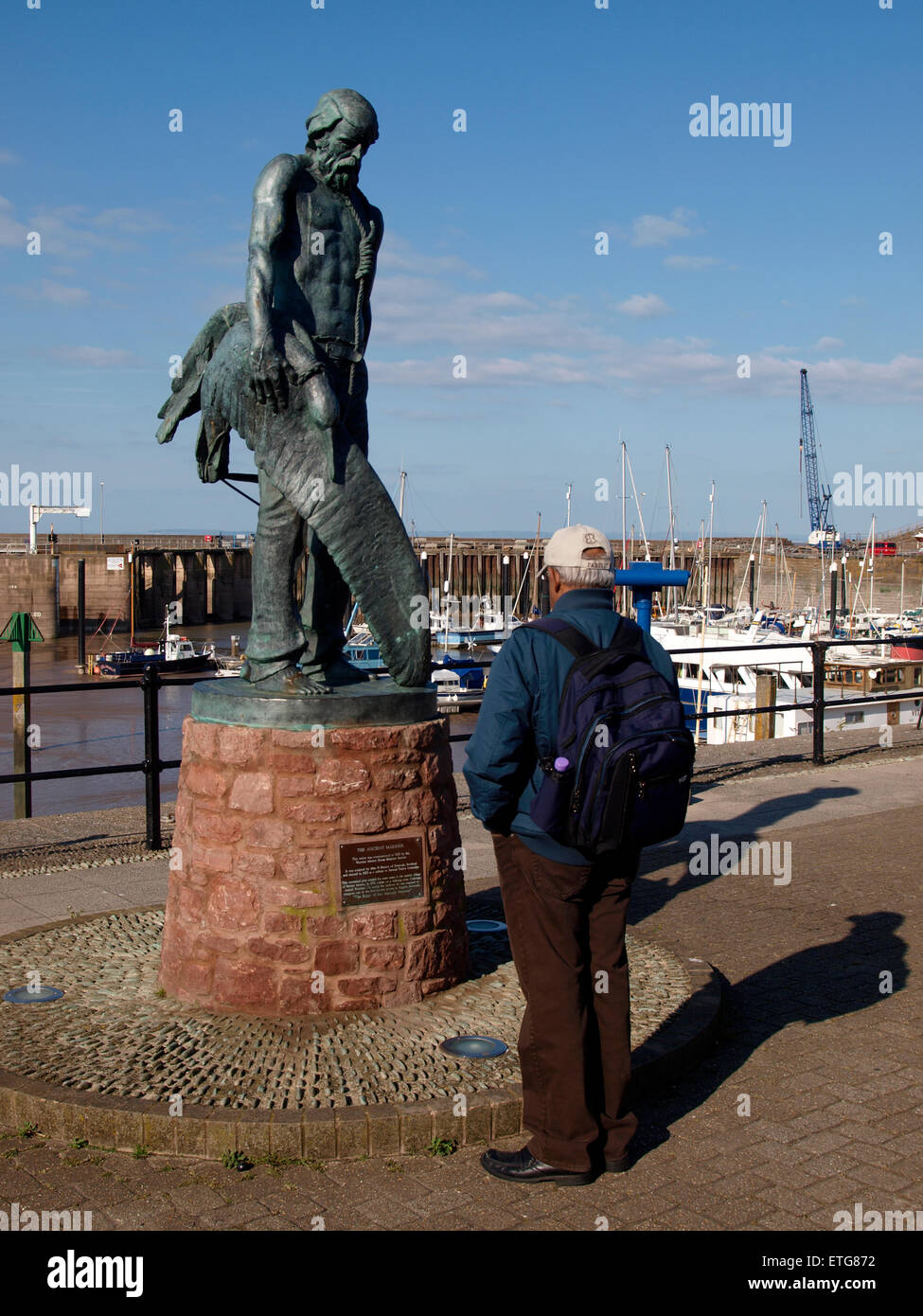 Man looking at statue of the Ancient Mariner, Watchet Harbour, Somerset, UK Stock Photo