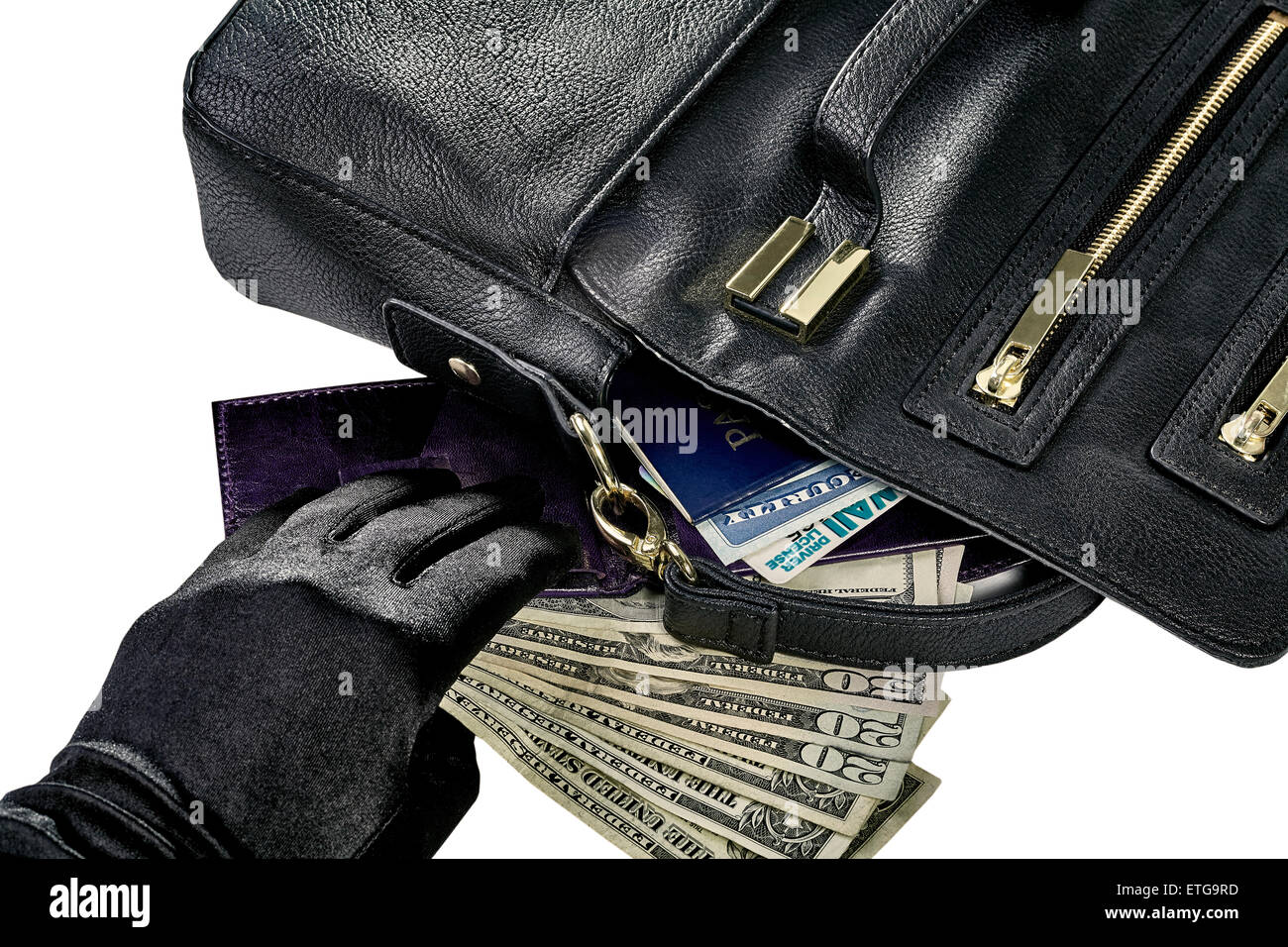 Women's purse with contents spilled including money, wallet, passport, social security card and driver's license and a hand reac Stock Photo