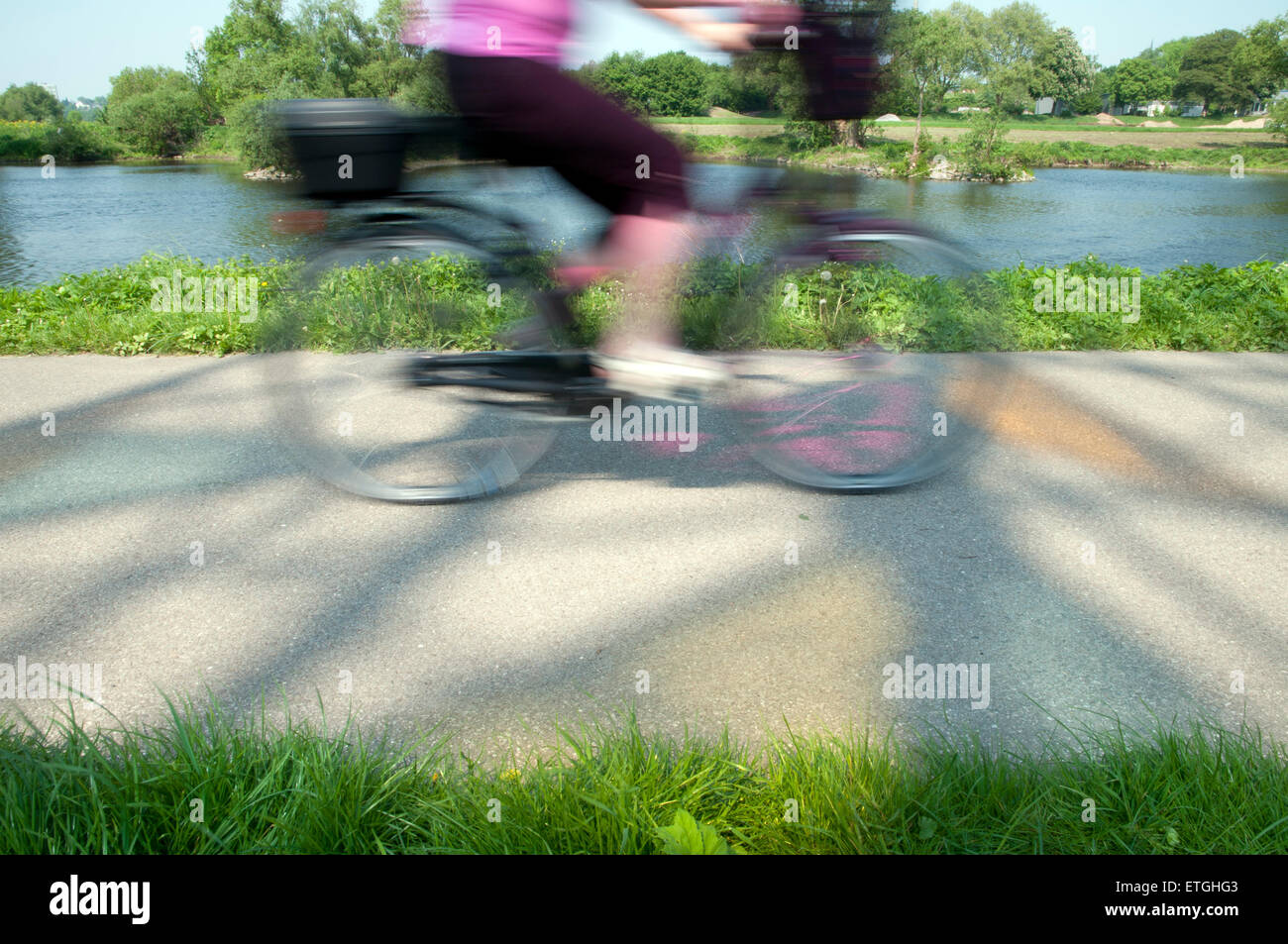 Blurred bicyclist on a bike road with colorful shadows at river ruhr north rhineland-westphalia Germany Europe Stock Photo
