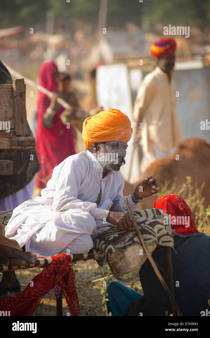 Rajasthani man in distinctive white attire and orange turban, smoking. Pushkar, Rajasthan, India Stock Photo
