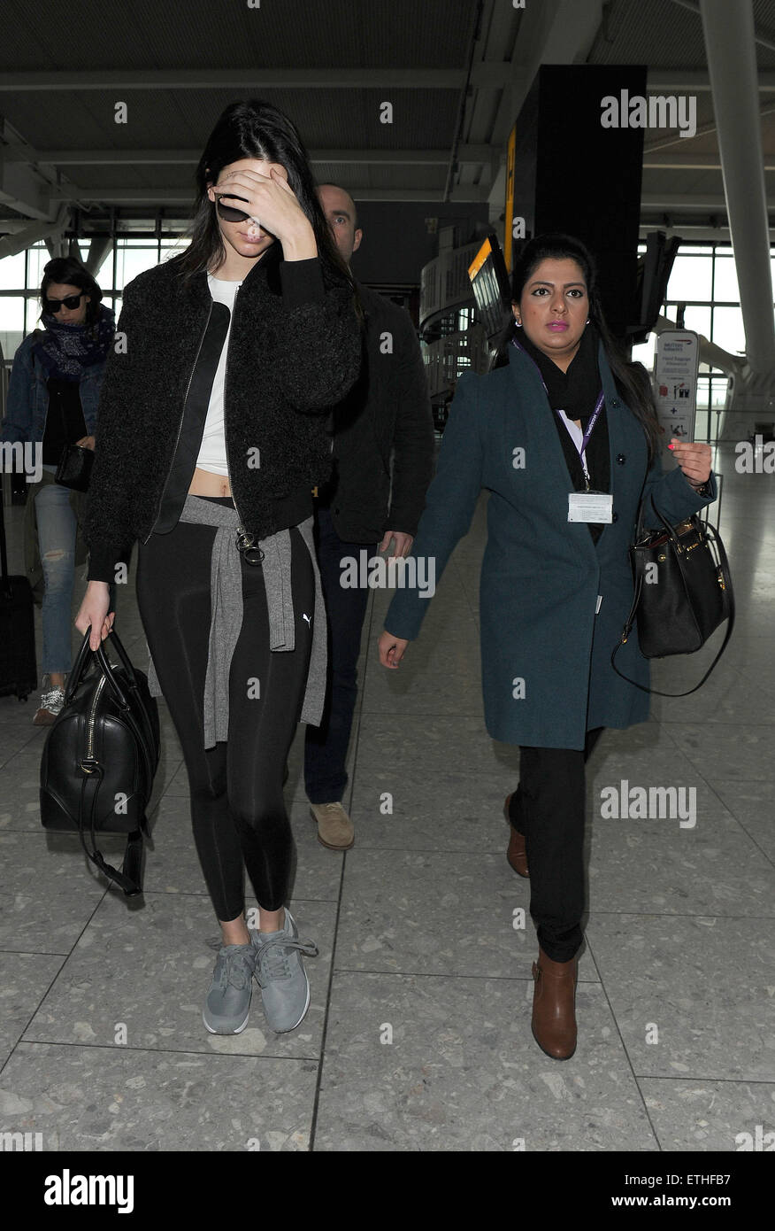 Kendall Jenner arriving at Heathrow Airport. Kendall appeared rather  camera-shy, and despite the gloomy weather, wore a pair of sunglasses, and  put her hand over her face as she made her way