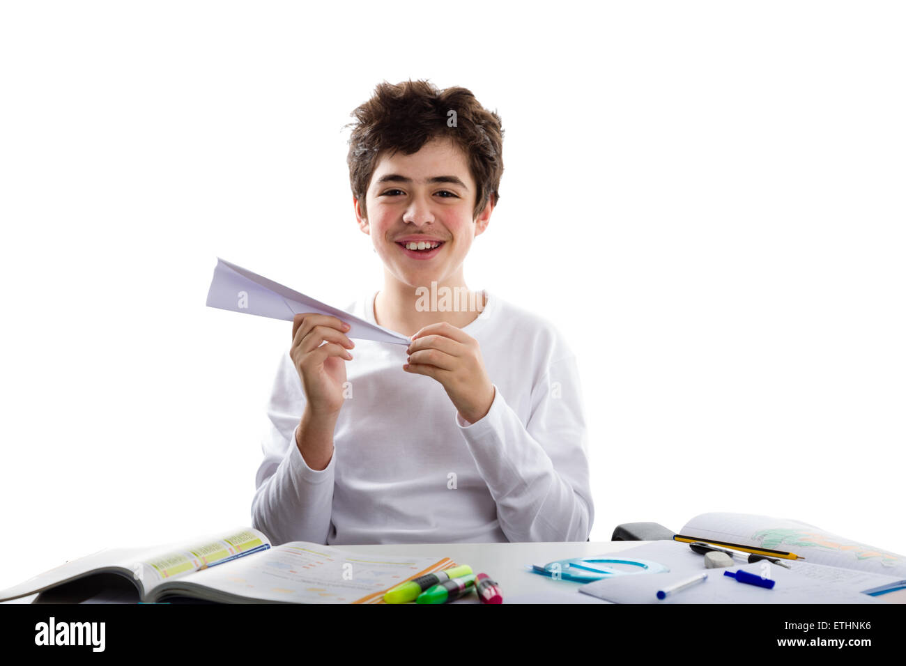 Boy Using Paper A caucasian boy is playing with a paper airplane sitting in front of ...