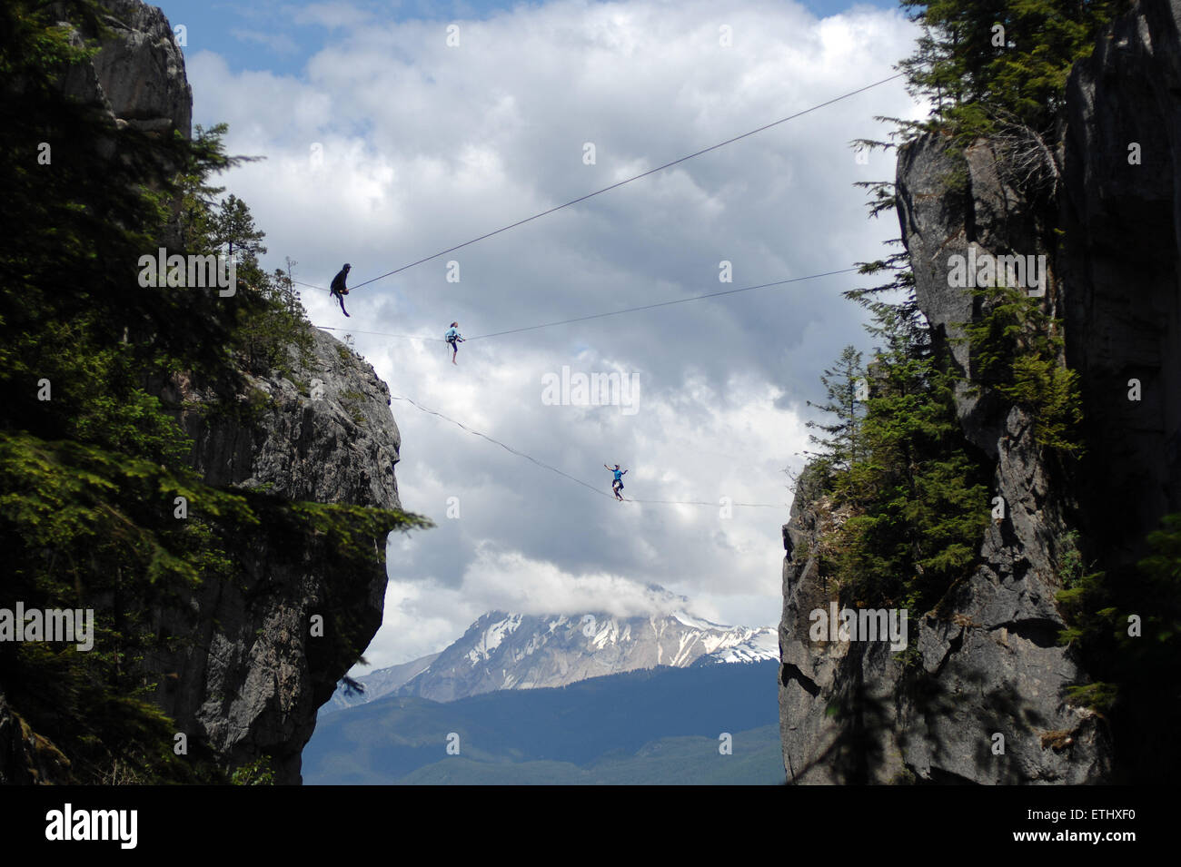 Squamish, Canada. 13th June, 2015. Adventure athletes walk the highline rigged across the gully of the Stawamus Chief peaks during the 2015 International Highlining Meet in Squamish, BC, Canada, on June 13, 2015. Highliners from across the world gather in Squamish to tackle The Chief. Highlining is an extreme sport in which adventurers walk across a rope from one cliff to another. Highlining started in the Yosemite Valley in California. Credit:  Sergei Bachlakov/Xinhua/Alamy Live News Stock Photo