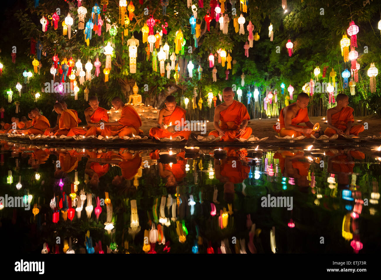 CHIANG MAI, THAILAND - NOVEMBER 6, 2014: Young Buddhist monks sit meditating at a festival of lights loi krathong ceremony. Stock Photo