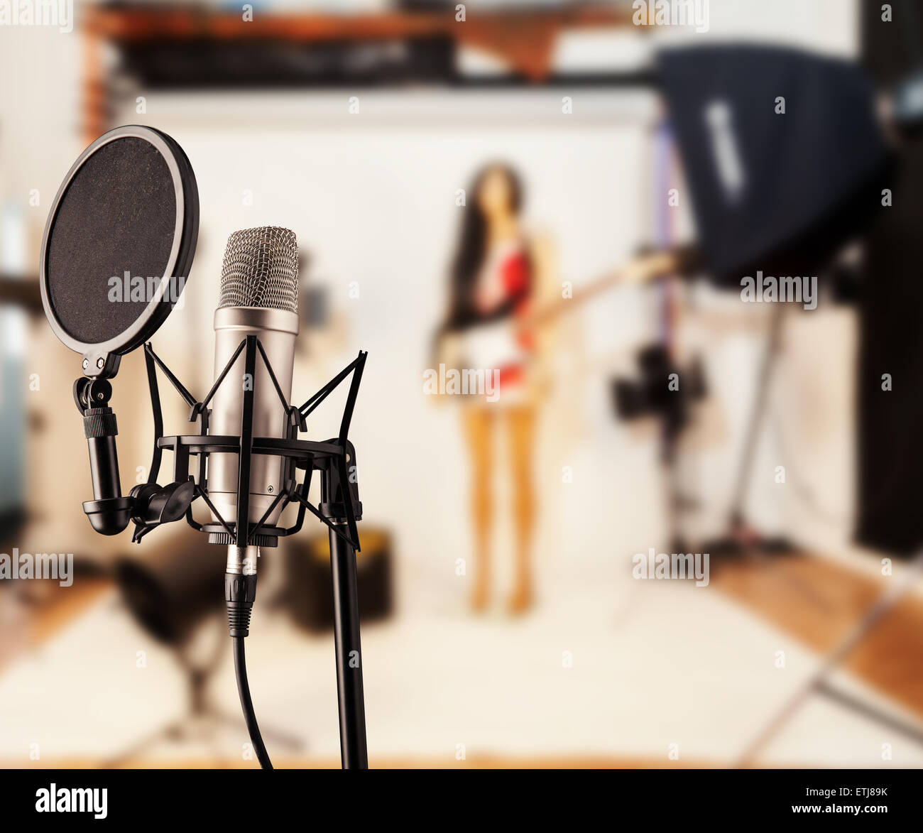 Detail of singing microphone in studio with blur guitar player on background Stock Photo