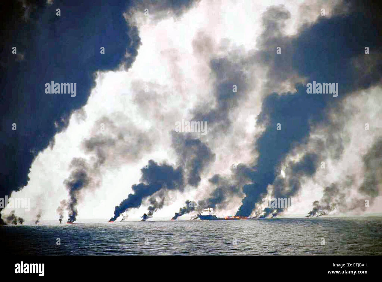 Dark clouds fill the sky as shrimp boats use a boom to gather crude oil during a controlled surface burn following the BP Deepwater Horizon oil spill disaster as efforts to contain and clean the millions of gallons of crew continue June 19, 2010 in the Gulf of Mexico. Stock Photo