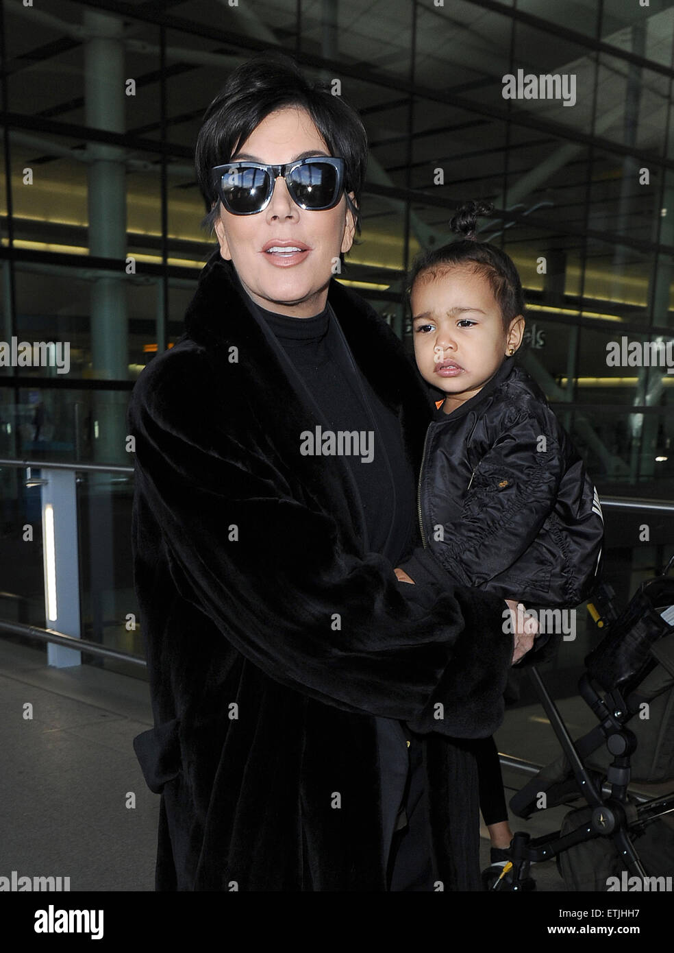 Kris Jenner, wearing a pair of Kanye West x Adidas Originals Yeezy 750  Boost, arrives at Heathrow Airport carrying baby North West, who was  wearing a 'Yeezus Tour" bomber jacket in support