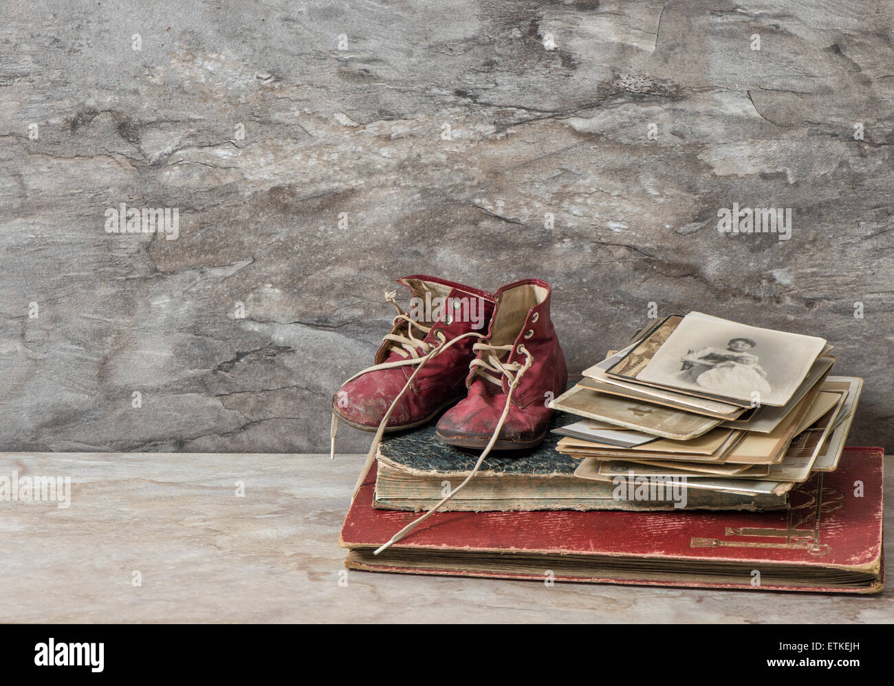 Antique books, photos, and baby shoes. Nostalgic still life with stone background Stock Photo