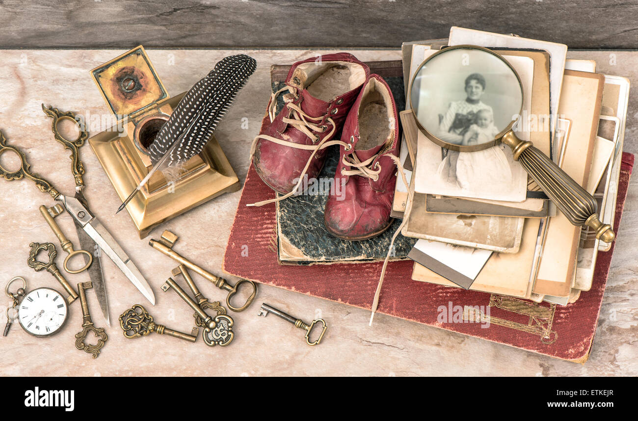 Antique books and photos, keys and writing accessories. Nostalgic still life with baby shoes Stock Photo