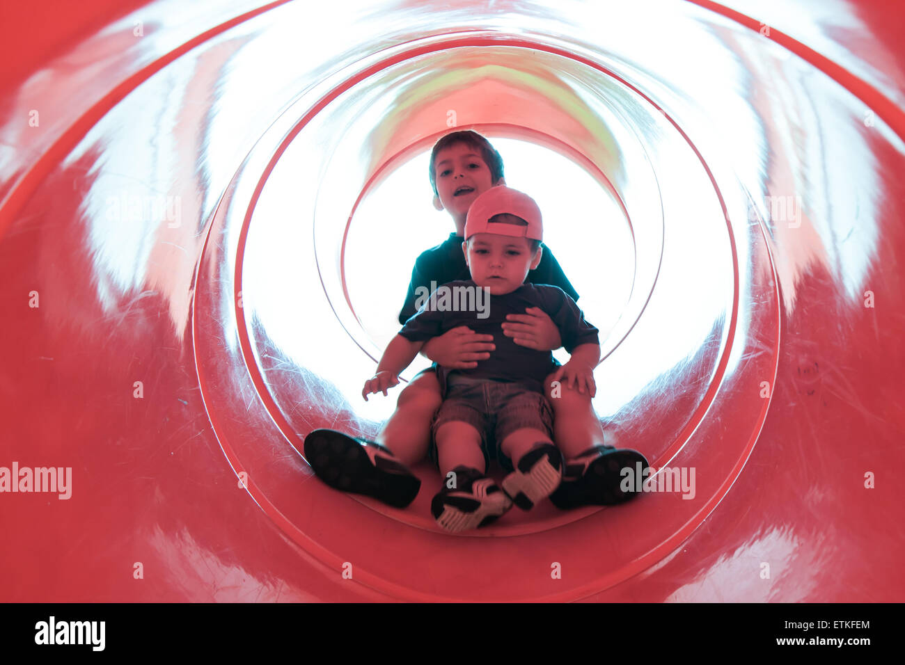 two children in red tube slide Stock Photo