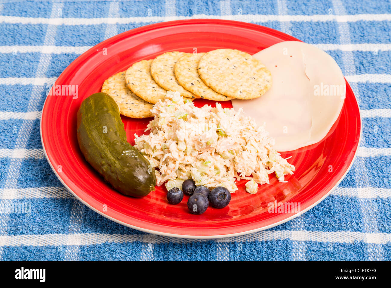 Homemade chicken salad on a red plate with crackers provolone cheese, a