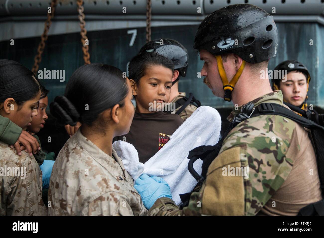 US Marines care for a young Indonesia refugee before transferring him to an Indonesian coast guard vessel from the USS Rushmore June 11, 2015 in the Pacific Ocean. The crew of the Rushmore rescued the group of refugees stranded between the Indonesian islands of Kalimantan and Sulawesi. Stock Photo