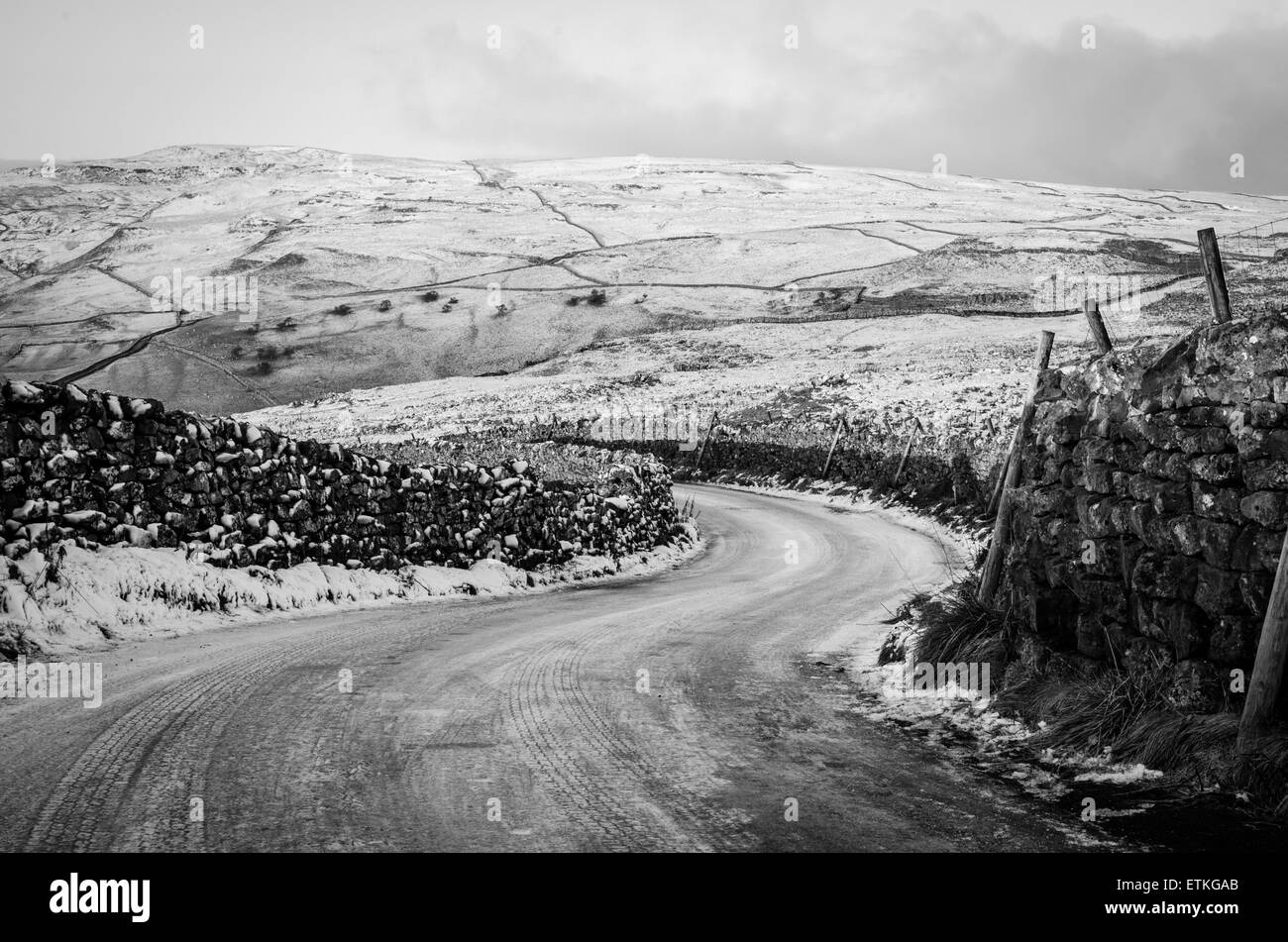 Sweeping bend covered in ice and snow on a road near Malham, Yorkshire Stock Photo
