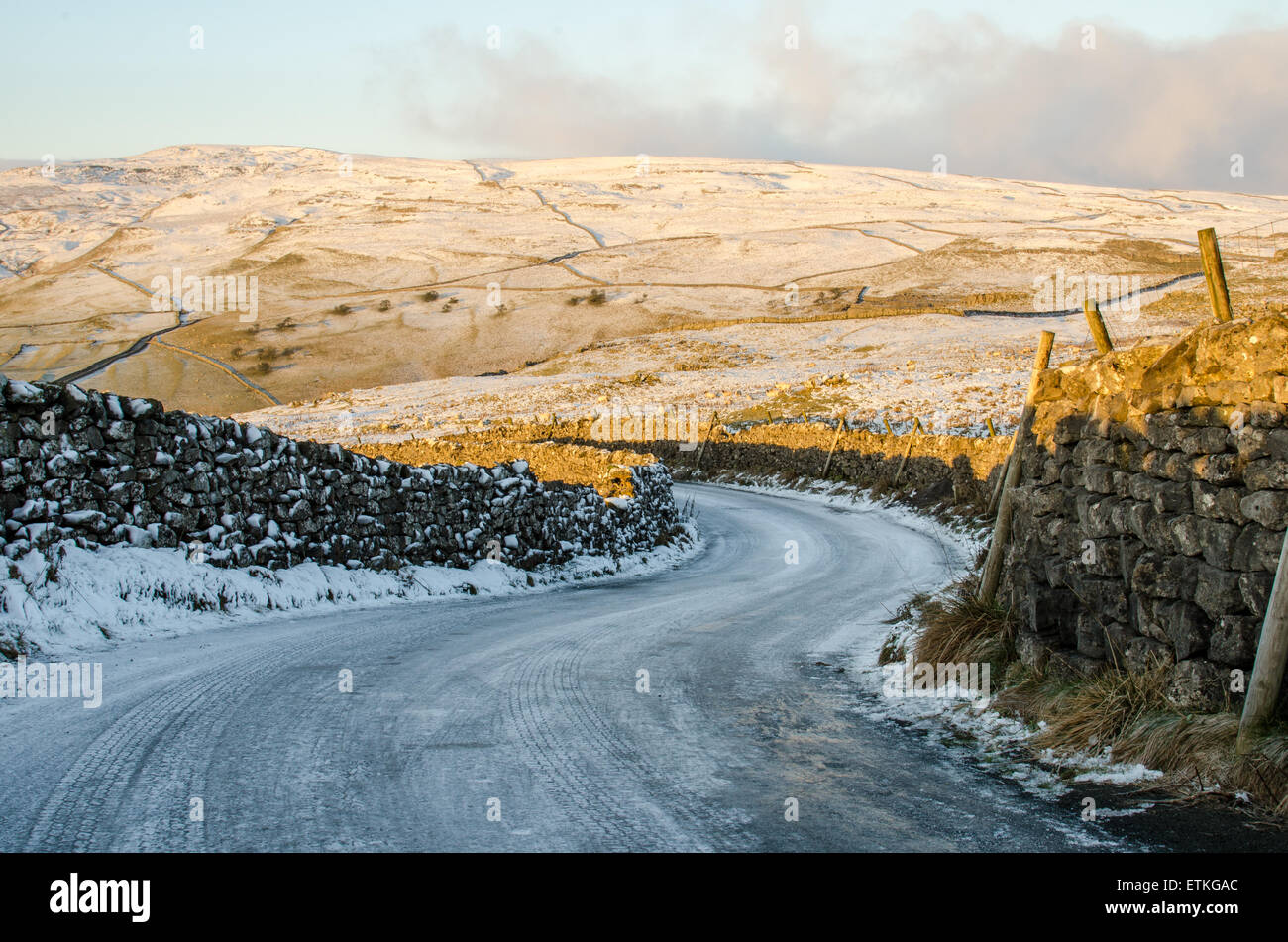 Sweeping bend covered in ice and snow on a road near Malham, Yorkshire Stock Photo