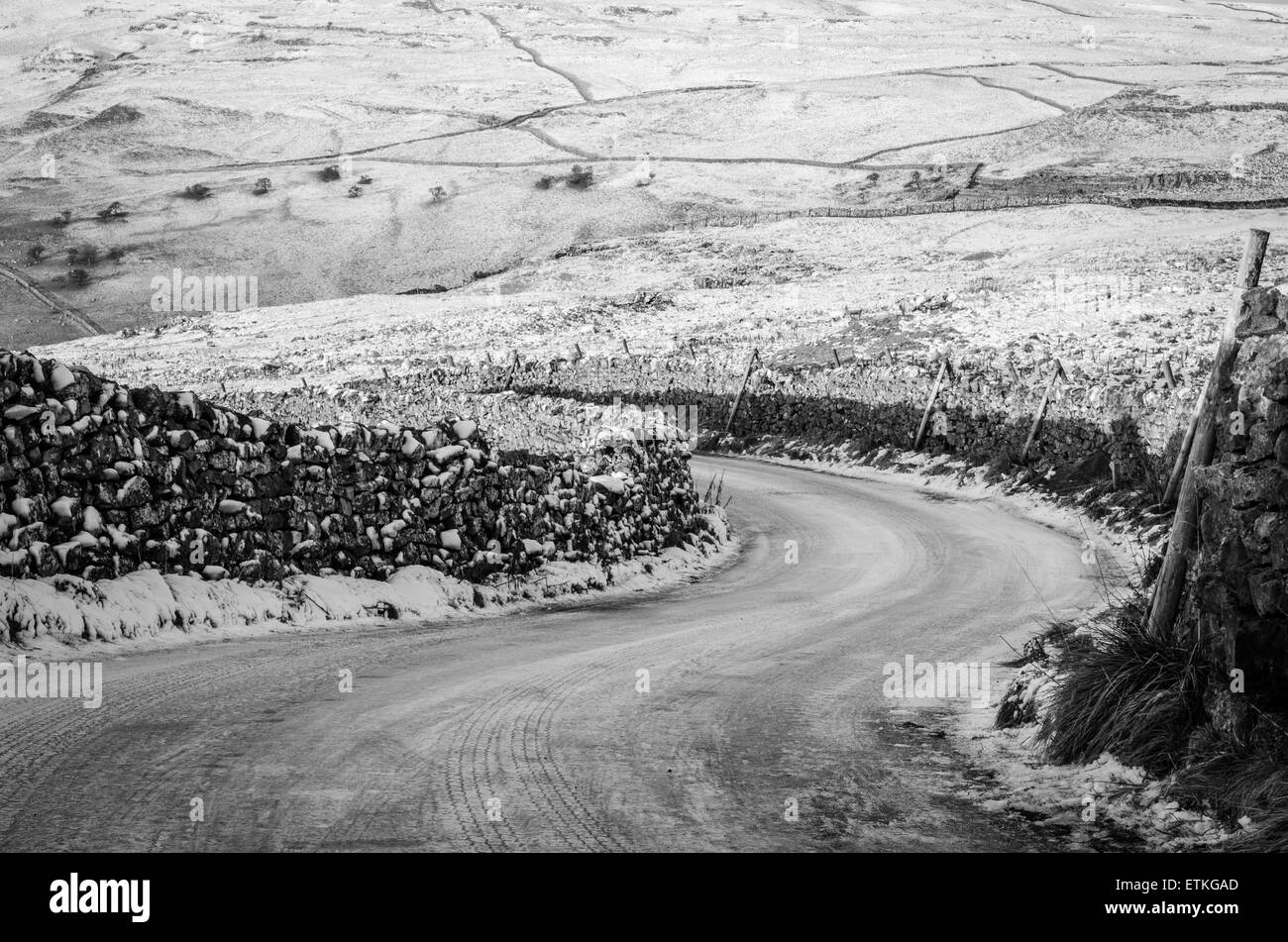 Sweeping bend covered in ice and snow on a road near Malham, Yorkshire Stock Photo