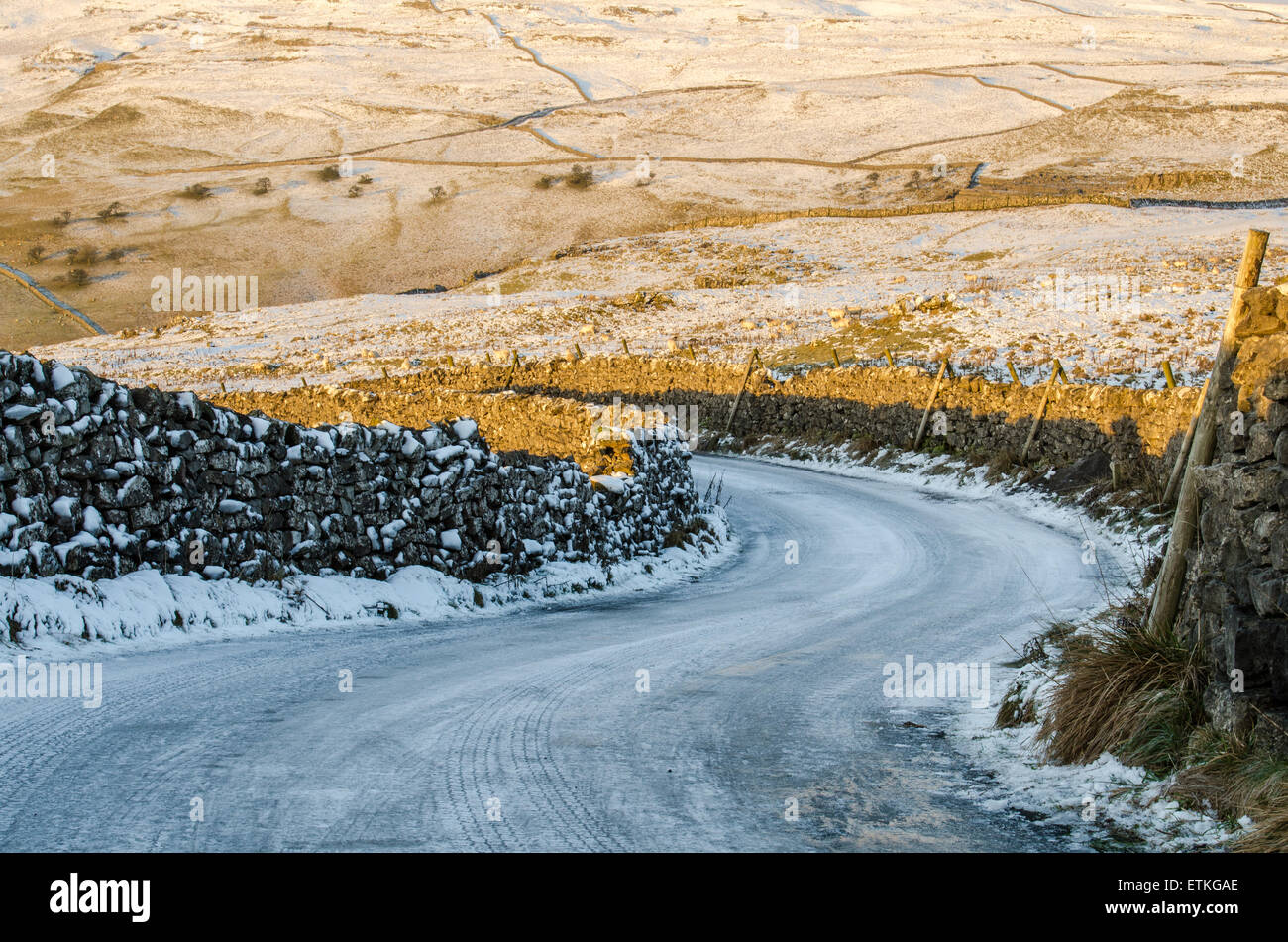 Sweeping bend covered in ice and snow on a road near Malham, Yorkshire Stock Photo
