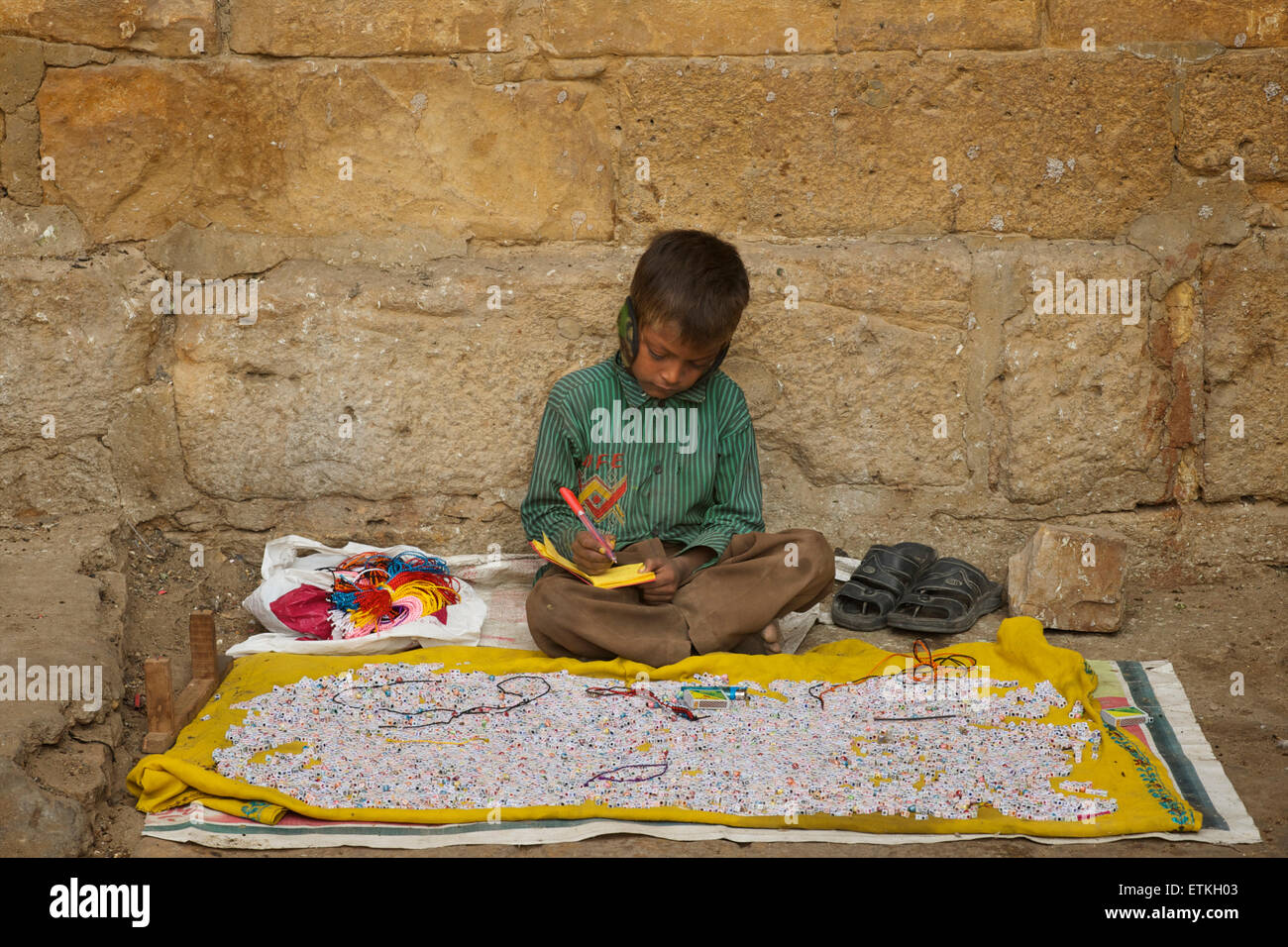 Indian boy making bead bracelets with alphabet beads. Jaisalmer, Rajasthan, India Stock Photo