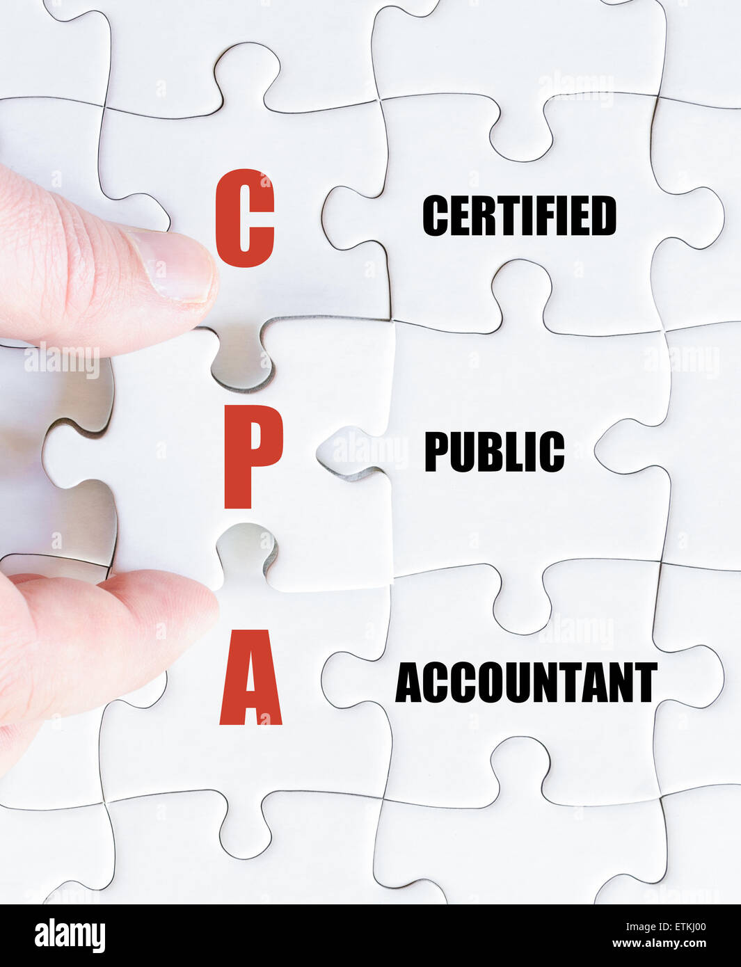 Hand of a business man completing the puzzle with the last missing piece.Concept image of Business Acronym CPA as Certified Public Accountant Stock Photo