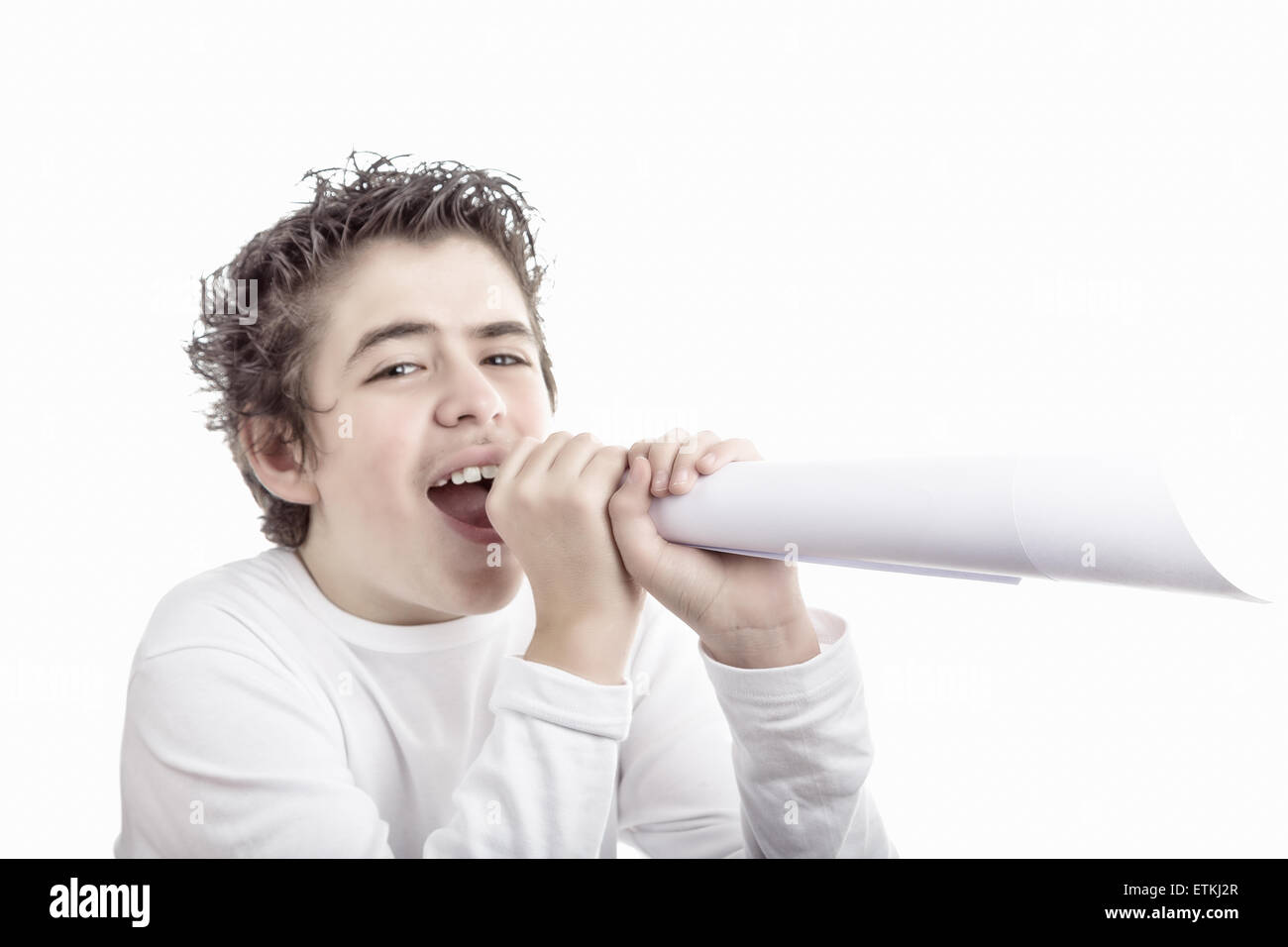 Handsome smiling  hispanic boy with medium length hair and questioning eyes shouts in a fake megaphone made with white paper Stock Photo