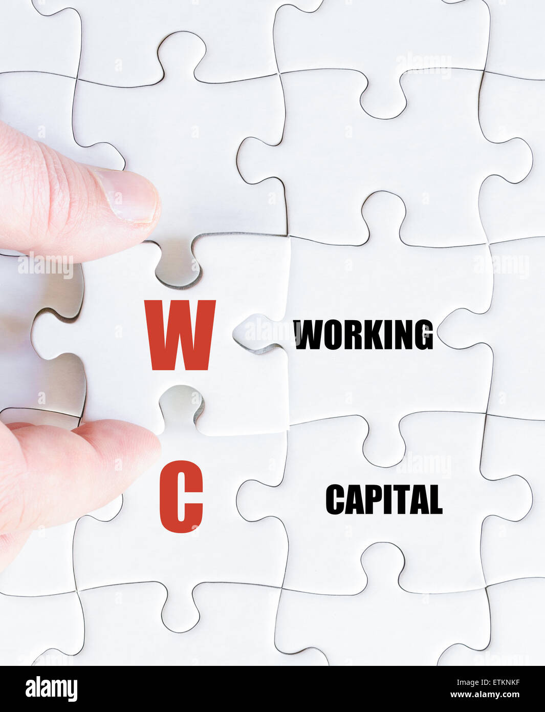 Hand of a business man completing the puzzle with the last missing piece.Concept image of Business Acronym WC as Working Capital Stock Photo