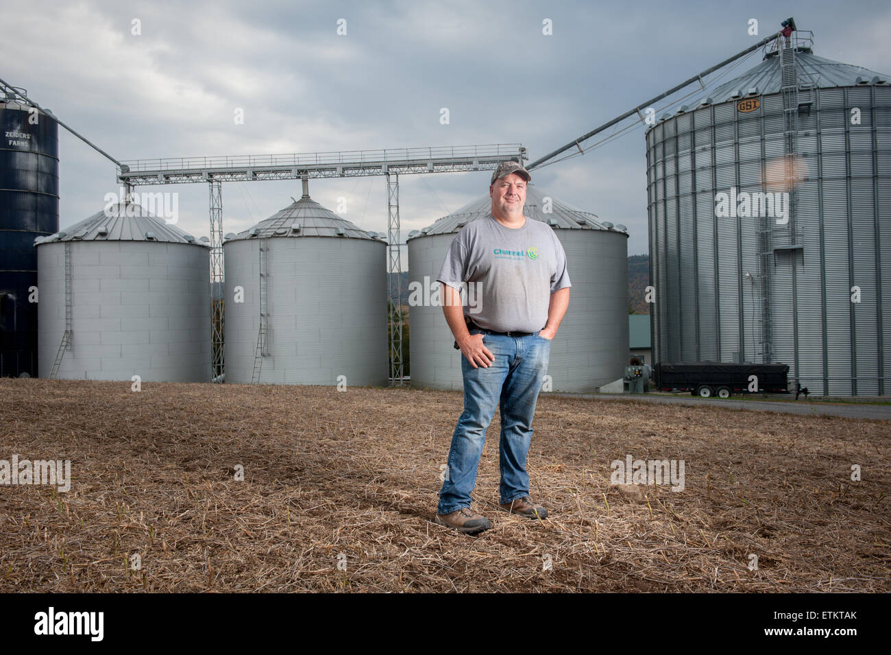 Farmer standing in front of steel grain silos in Dalmatia, Pennsylvania, USA Stock Photo