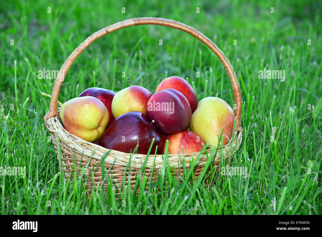 wicker basket with fruits on green grass Stock Photo - Alamy