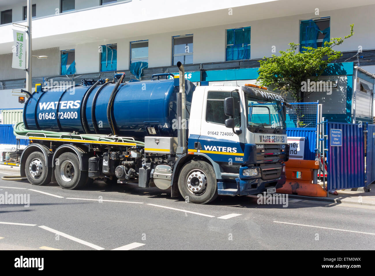 A waste water removal tank truck collecting waste from an Hotel construction site. Stock Photo