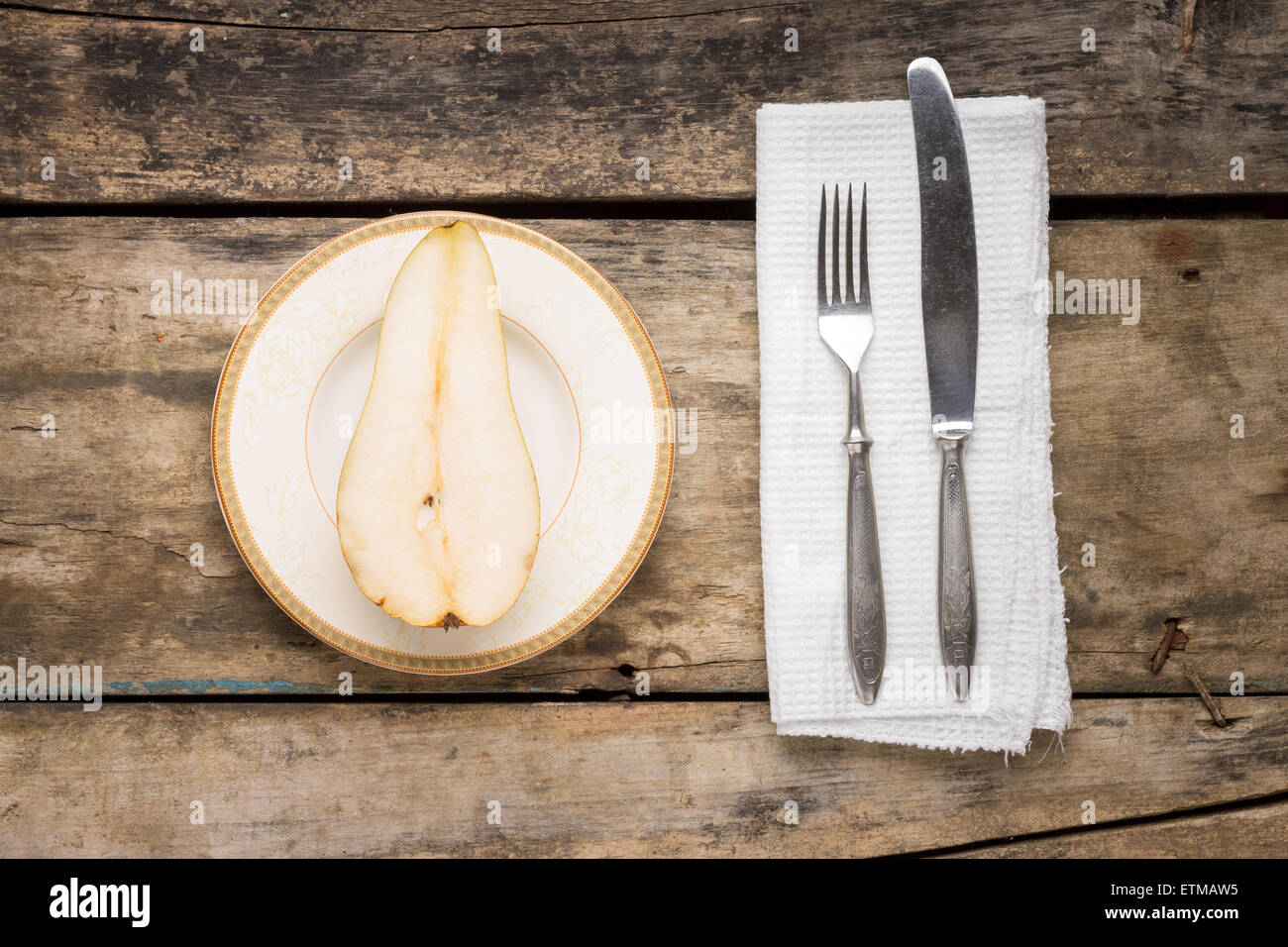 Cut in half big pear fruit with silverware on wooden table. Top view image dessert background. Stock Photo