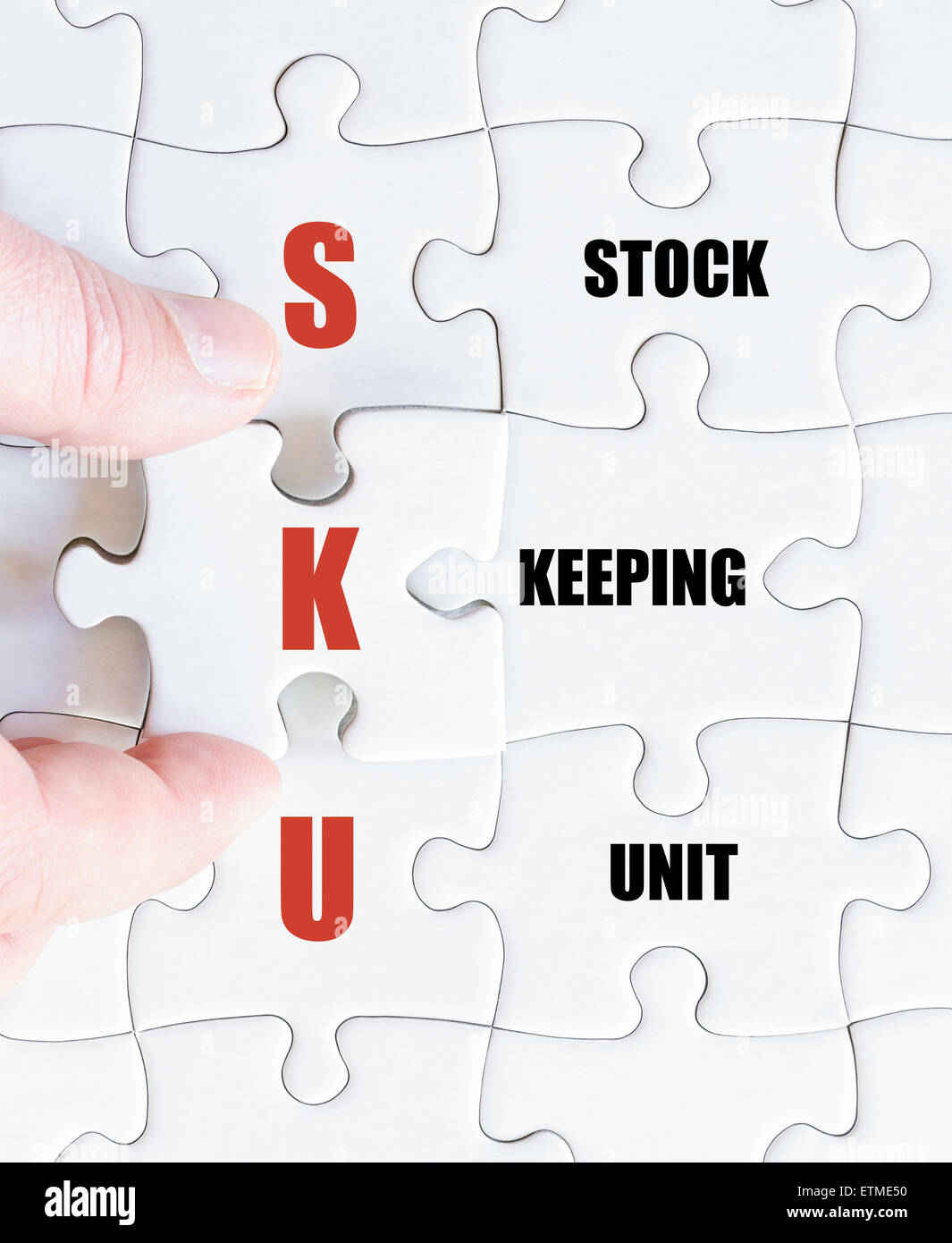Hand of a business man completing the puzzle with the last missing piece.Concept image of Business Acronym SKU as Stock Keeping Unit Stock Photo